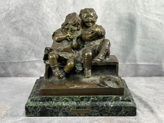 "Au Guignol" By Juan Clara(Spain, B.1875-1957) Bronze: A detailed bronze statue mounted on a polished green marble base, depicting two children engrossed in play. The work is signed by Spanish sculptor Juan Clara on the front of the bronze, and it feature