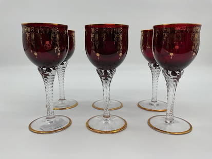 Vecchia Murano Ruby Red and Gold Wine Glass Set: This is a set of six handcrafted ruby red Murano glass wine goblets from Vecchia Murano, each adorned with intricate 24k gold embellishments and a clear, twisted stem. The design blends luxury with tr