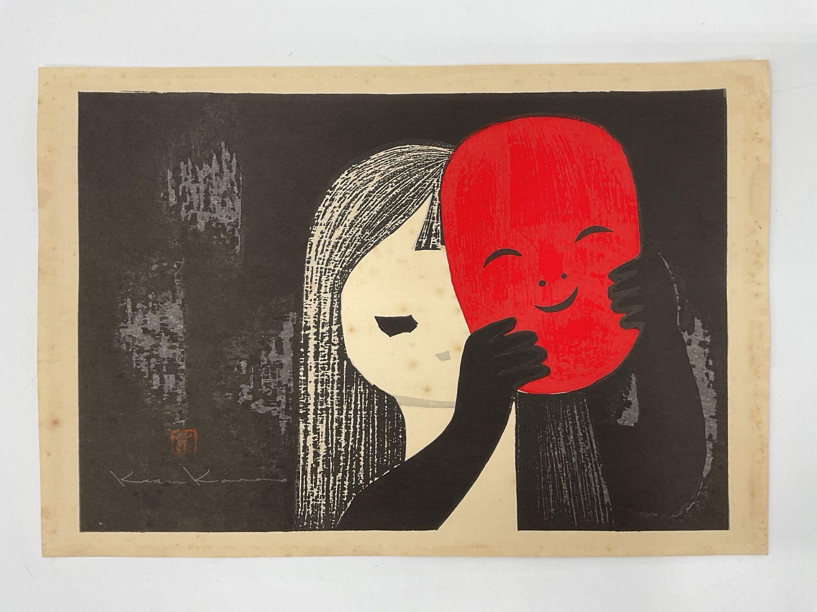 Smiling Mask by Kaoru Kawano (Japan, 1916-1965) Woodblock print: Striking Japanese woodblock print by Kaoru Kawano (1916–1965), depicting a young girl holding a vivid red smiling mask. Kawano’s signature minimalist style is evident in the flat planes of color a