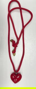 Red Lucite Heart Pendant on Rope Cord: Bold red heart-shaped pendant made of lucite or resin, suspended from a red woven cord with decorative brass-tone end caps. Features a knotted closure. Likely vintage costume jewelry, circa