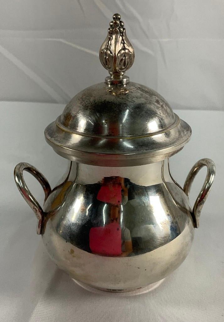 Silver plated Sugar Bowl: Elegantly designed silver plated sugar bowl with a decorative lid featuring a pointed finial.Two curved handles add to its functionality and aesthetic appeal.Lid fits securely, making it ideal for ser