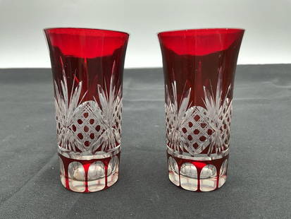 Pair of Bohemian Ruby Cut-to-Clear Crystal Glasses: Elegant pair of ruby red cut-to-clear crystal glasses with intricate lattice and starburst designs. The deep red overlay is finely cut to reveal the clear glass underneath in a traditional Bohemian pa