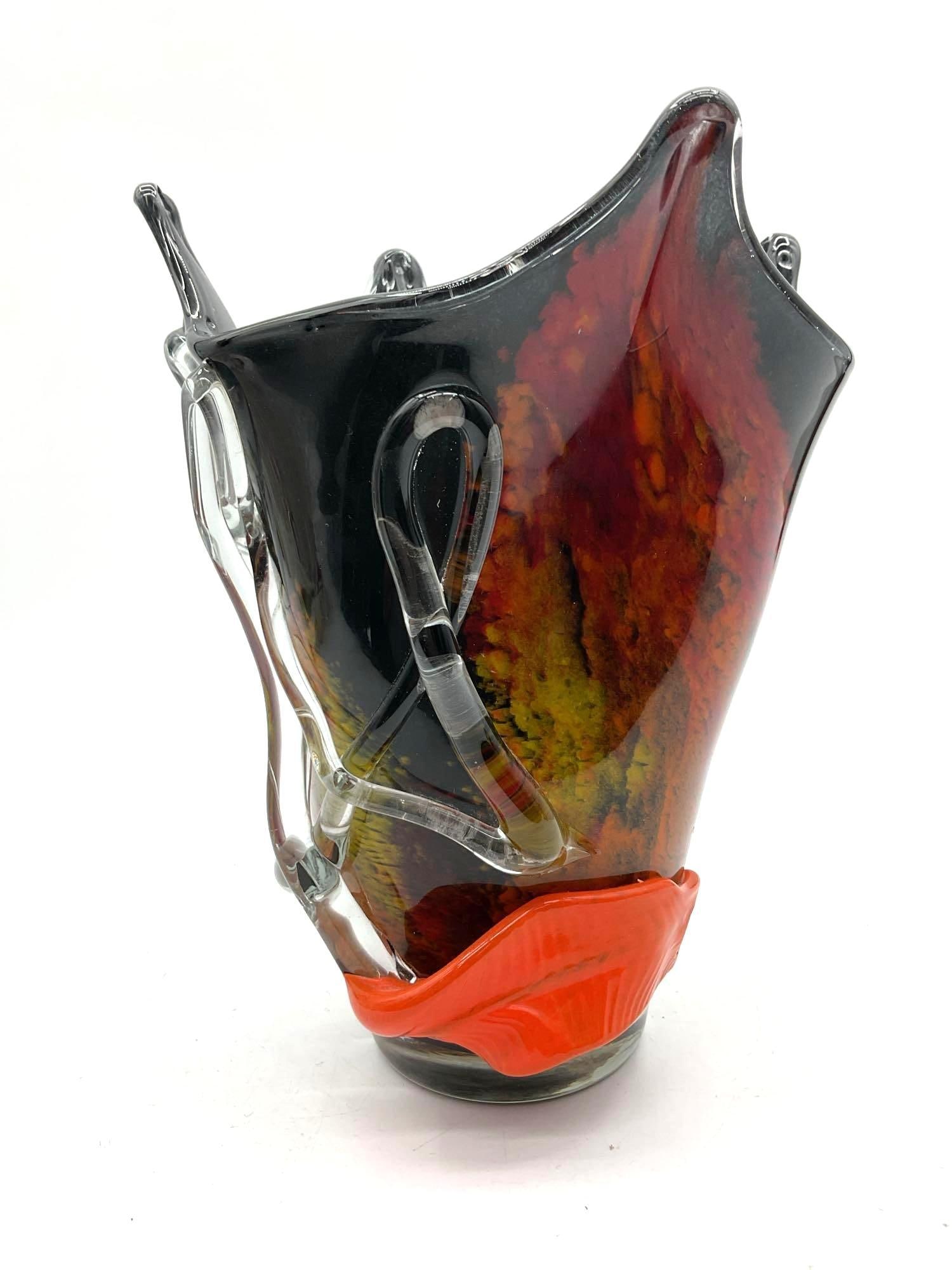 Murano Style Black and Red Art Glass Vase with Clear Ribbon Accents: Handblown vase featuring a dramatic flared black rim, vivid red and yellow swirls, and applied clear glass ribbon detailing. Dimensions: H10in L8in W8in Medium: Blown art glass