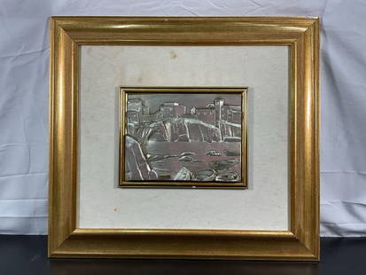 Silver Relief Coastal Scene: A striking metal relief artwork depicting a coastal village perched on cliffs overlooking a body of water. The scene features small boats resting along the shore and a stone bridge connecting the land