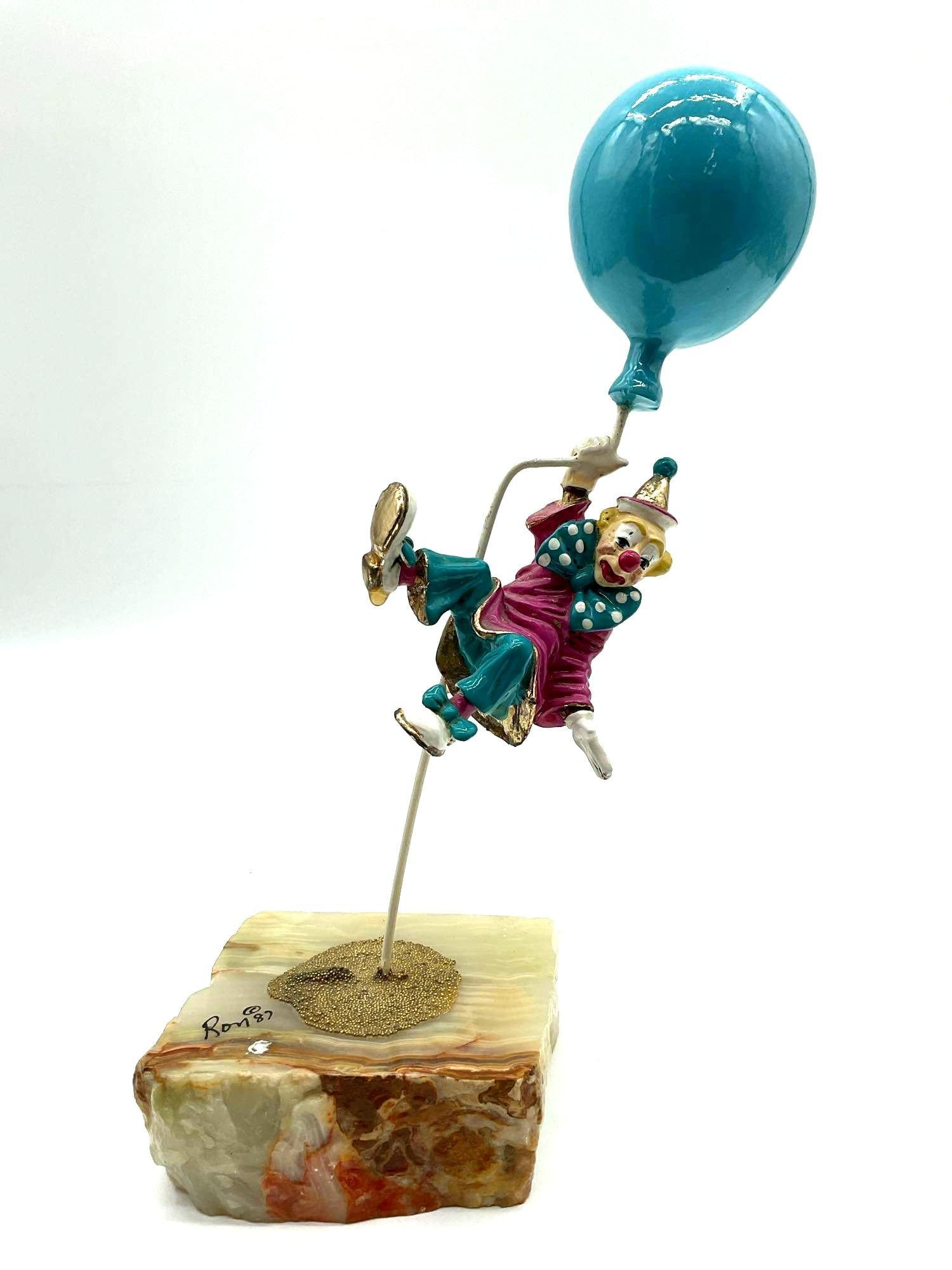 Clown with Blue Balloon by Ron Lee: Whimsical Ron Lee sculpture of a clown in midair, holding onto a bright blue balloon, dressed in a colorful outfit with teal shoes and a pink coat. Signed and dated 1987. Dimensions: H11in L4in W4in M