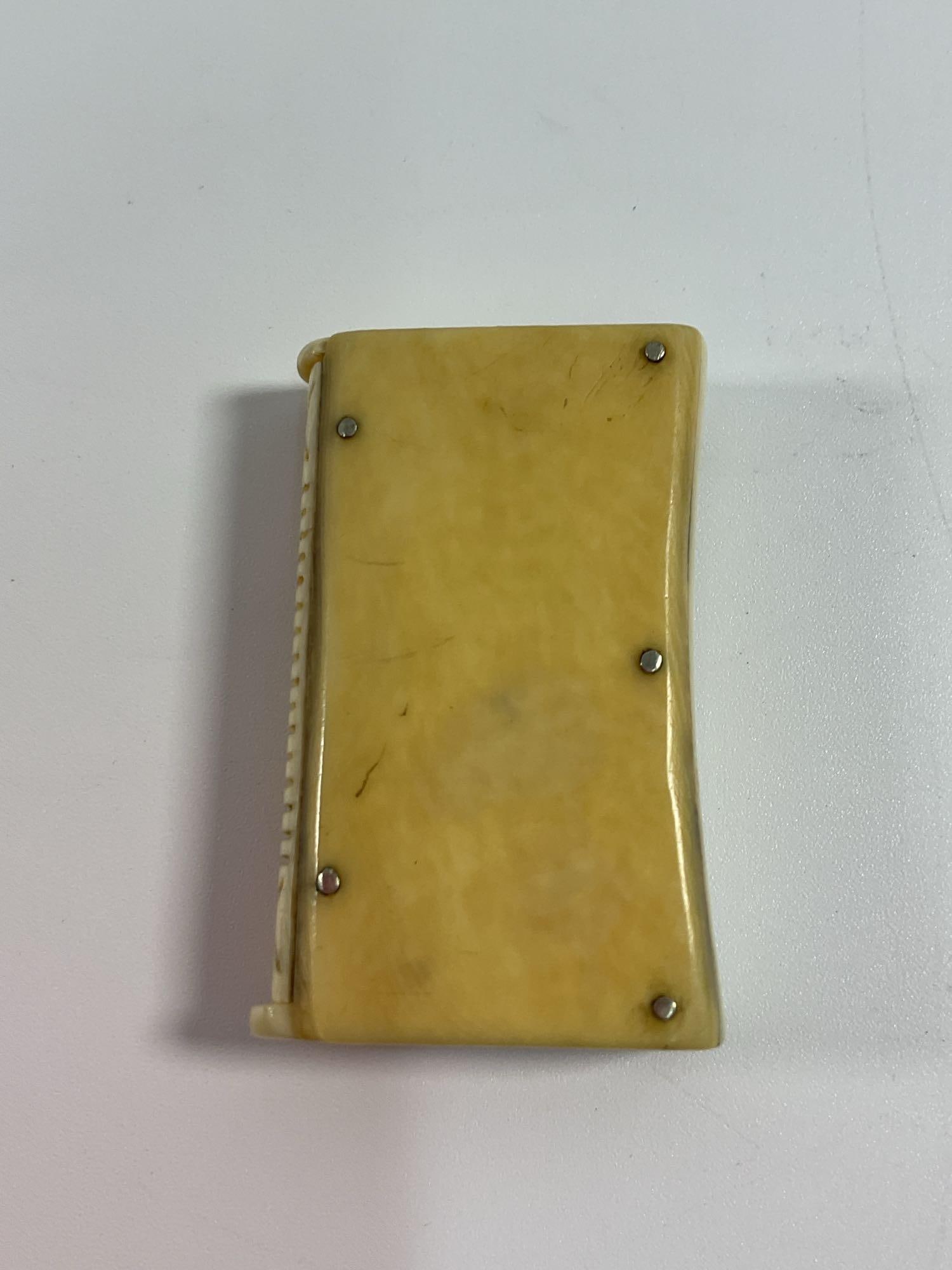 Antique Carved Bone Match Safe: A unique antique match safe crafted from carved bone or ivory, featuring riveted metal fittings securing the panels. The surface has a smooth, aged patina with visible natural grain patterns, adding t