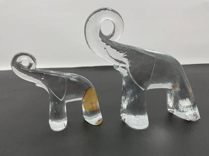 Modern Abstract Glass Elephant Pair - Box 2: A set of two clear glass elephant figurines with a sleek, minimalist design. The elongated forms feature smooth curves, hollowed legs, and gracefully curled trunks, giving them a contemporary and arti