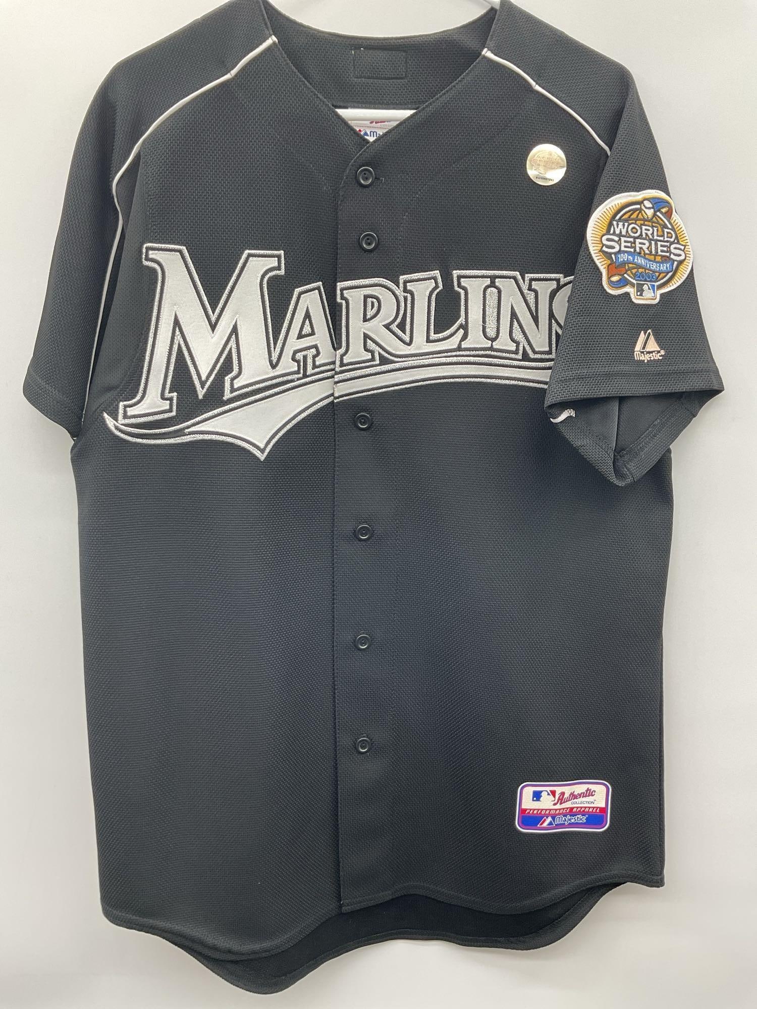 Florida Marlins Black Jersey: Florida Marlins black jersey, still sealed in its original plastic wrapping. The logo is partially visible, but details on the number or player association remain obscured. Likely a vintage or collect