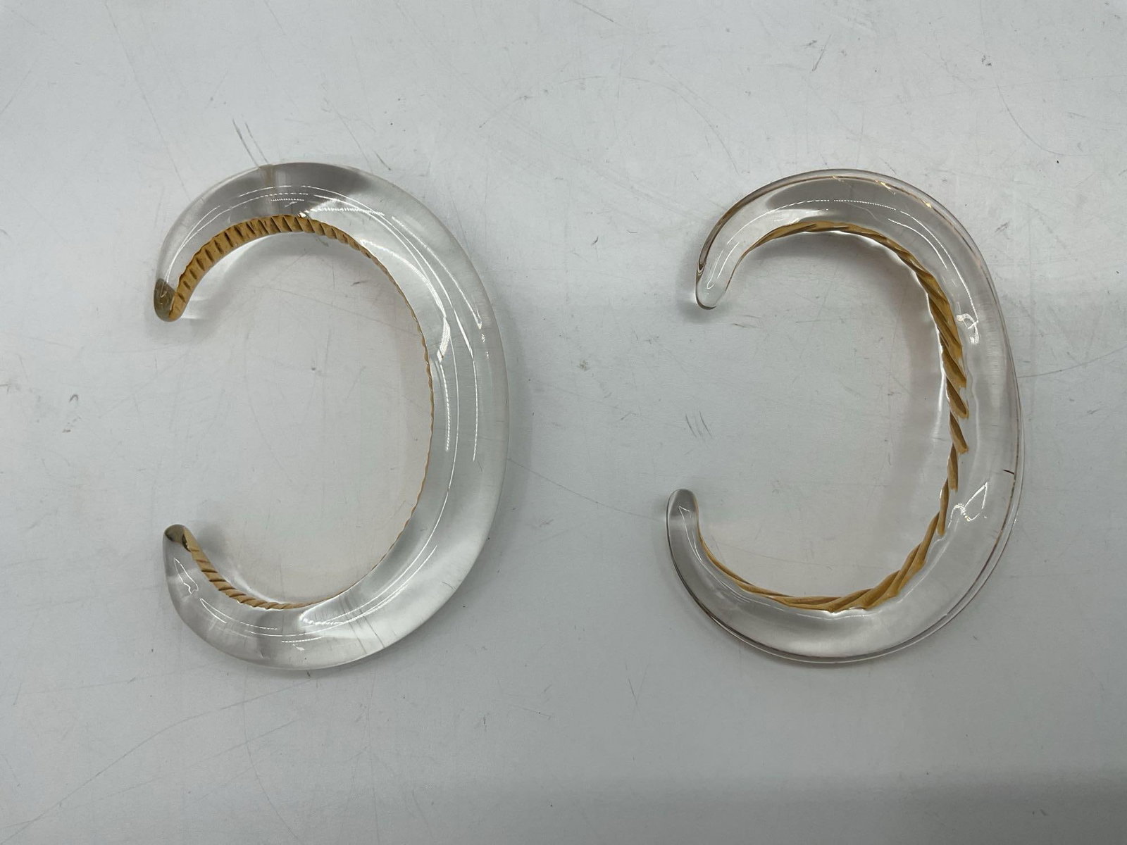 Pair of Sculptural Cuff Bracelets in Silver and Gold Tone: Stylish modernist cuff bracelet pair, one in polished silver tone and one in warm gold tone finish. Each features a sleek wave-like design with a ribbed inner texture. Dimensions: L3in W2.5in Medium: