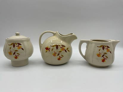 Vintage Hall's Superior Autumn Leaf Ceramic Serving Set (3 Pieces) - Hall China, Jewel Tea Company: Description: Set includes a round pitcher, a lidded sugar jar, and a rectangular teapot, all decorated with stylized orange, yellow, and brown floral designs. Likely American mid-century kitchenware,