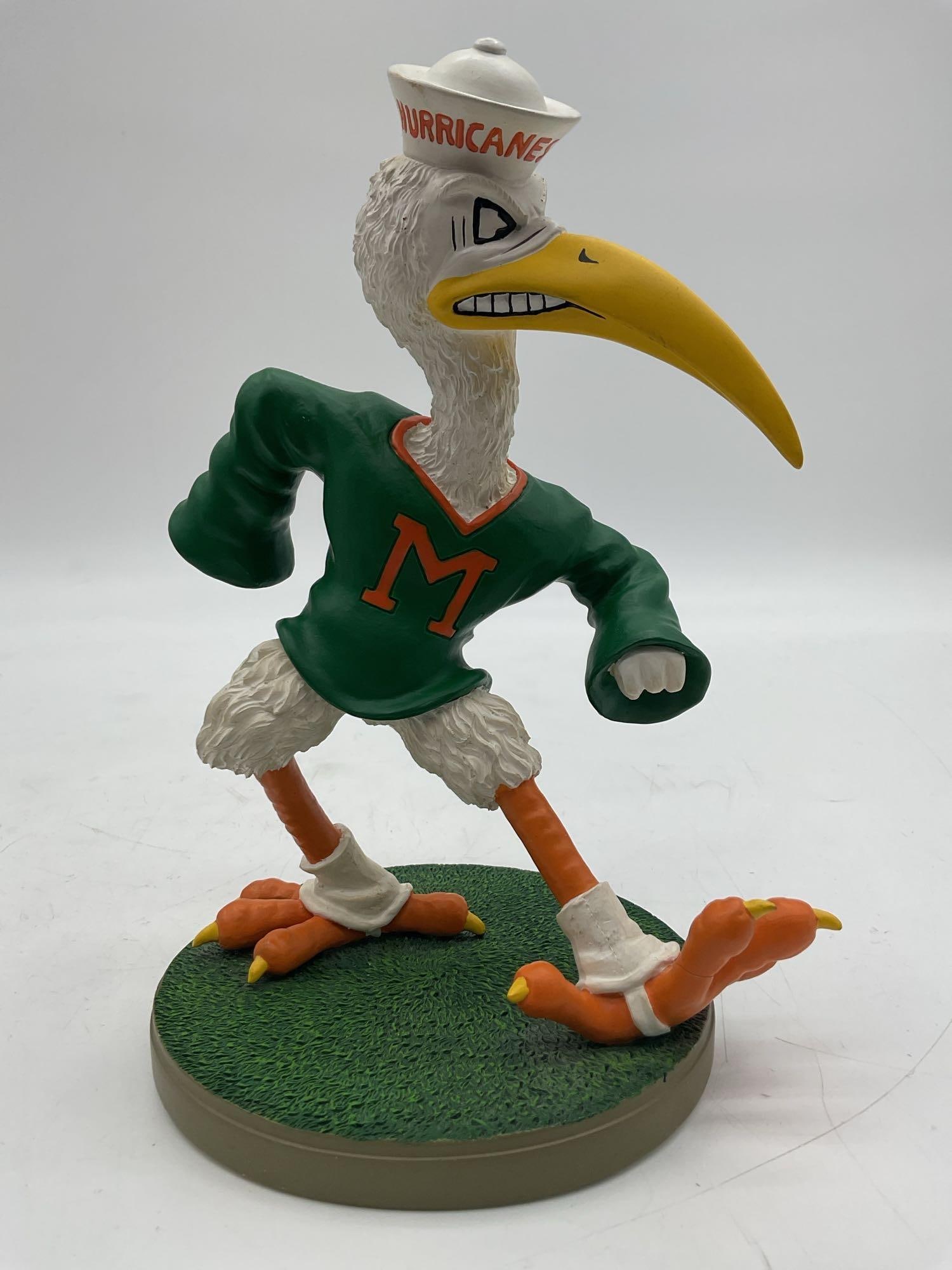 University of Miami Hurricanes Sebastian the Ibis Figurine: This University of Miami Hurricanes figurine features Sebastian the Ibis, the school’s beloved mascot, in a dynamic pose wearing a vintage-style green "M" jersey and his classic sailor hat w