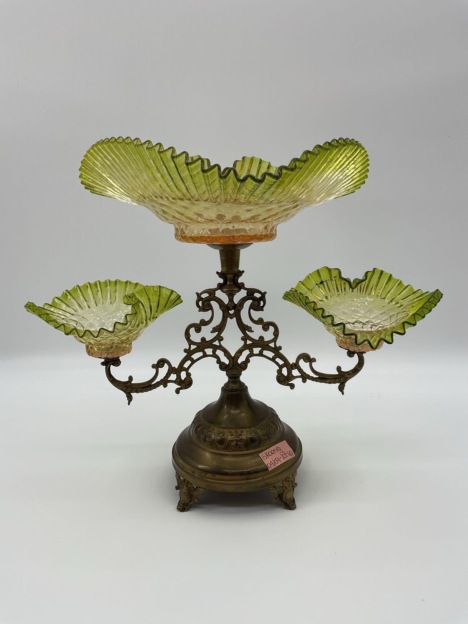 Vintage Victorian-Style Epergne with Vaseline Glass Bowls: This ornate centerpiece features three fluted, ruffled-edge glass bowls in a pale green-yellow hue, commonly referred to as vaseline glass. The central bowl is elevated above two side arms, all suppor