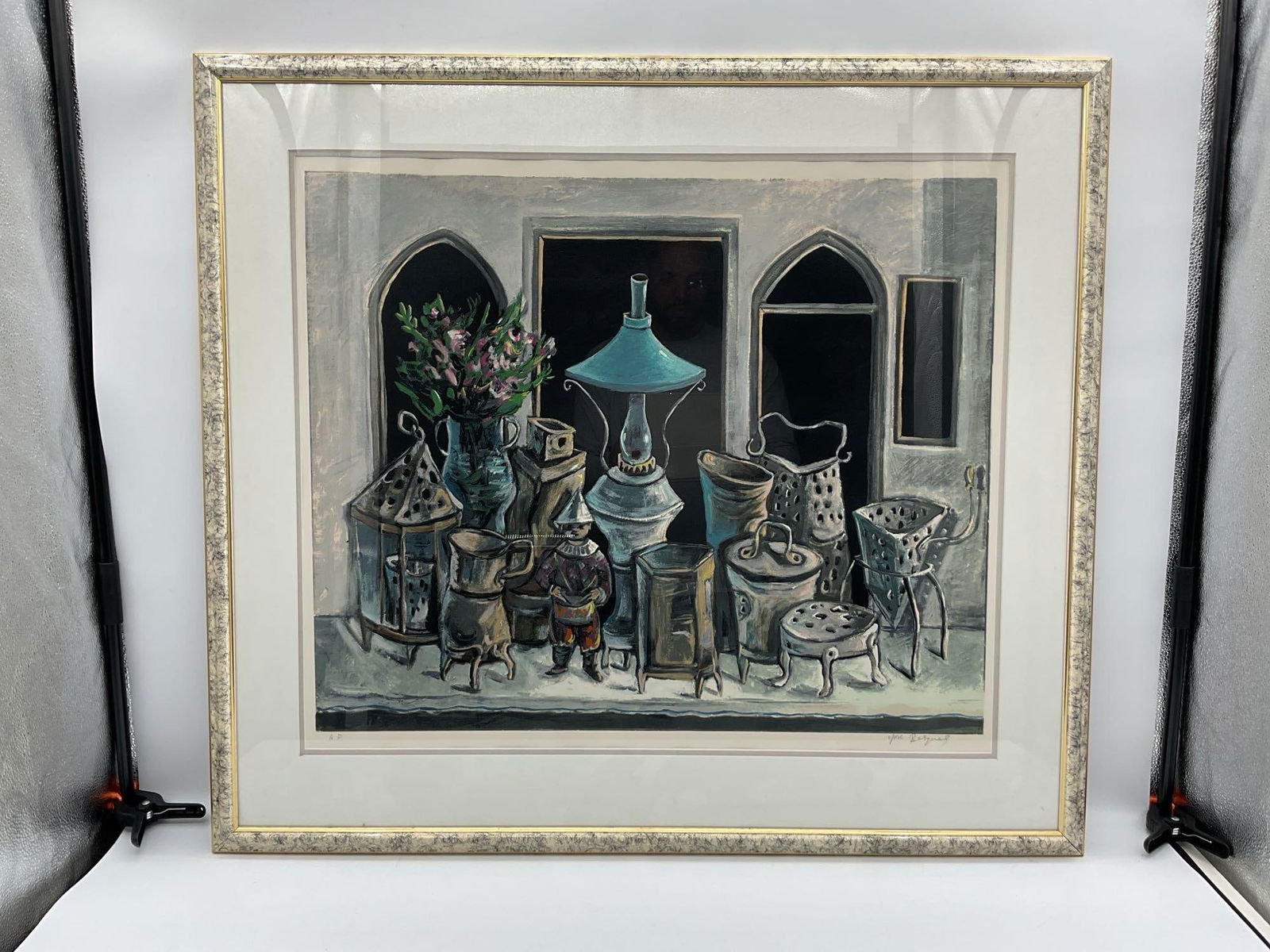 Marketplace Window by Yosl Bergner (Israel, 1920-2017) Lithograph: Description: A richly detailed still life showing an assortment of metal vessels, lanterns, and decorative objects displayed in a storefront or market window. A blue hanging lamp and a bouquet of pink