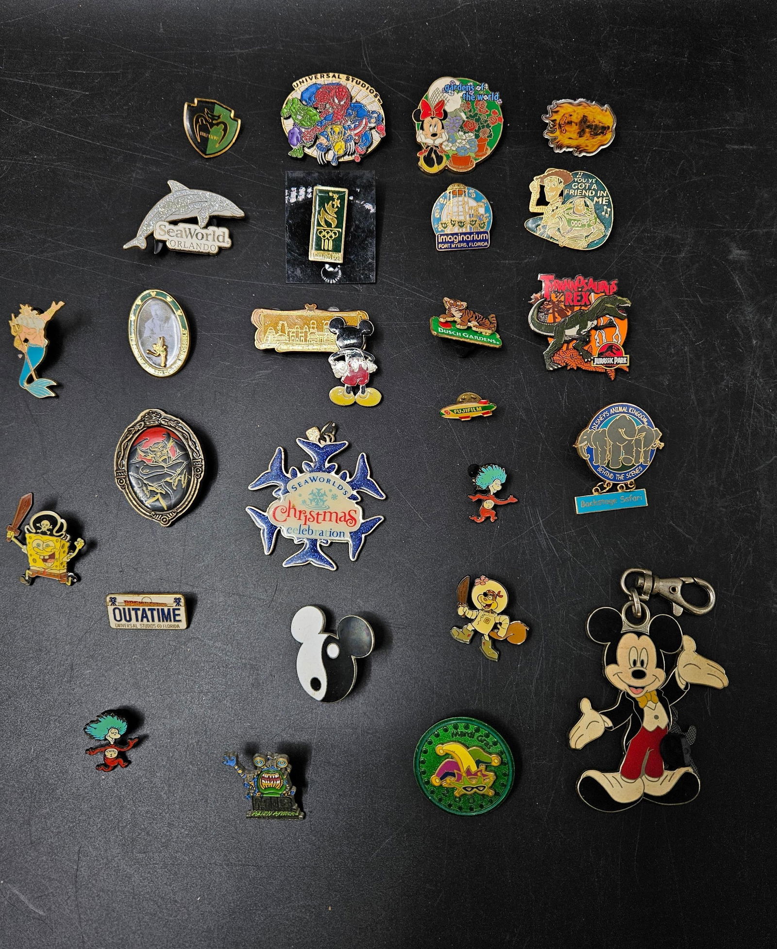 Collection of Pins: Collection of enamel pins featuring popular characters and attractions. Highlights include Mickey Mouse, SpongeBob, SeaWorld, Universal Studios, and Imaginarium designs. Mix of vintage and modern, som