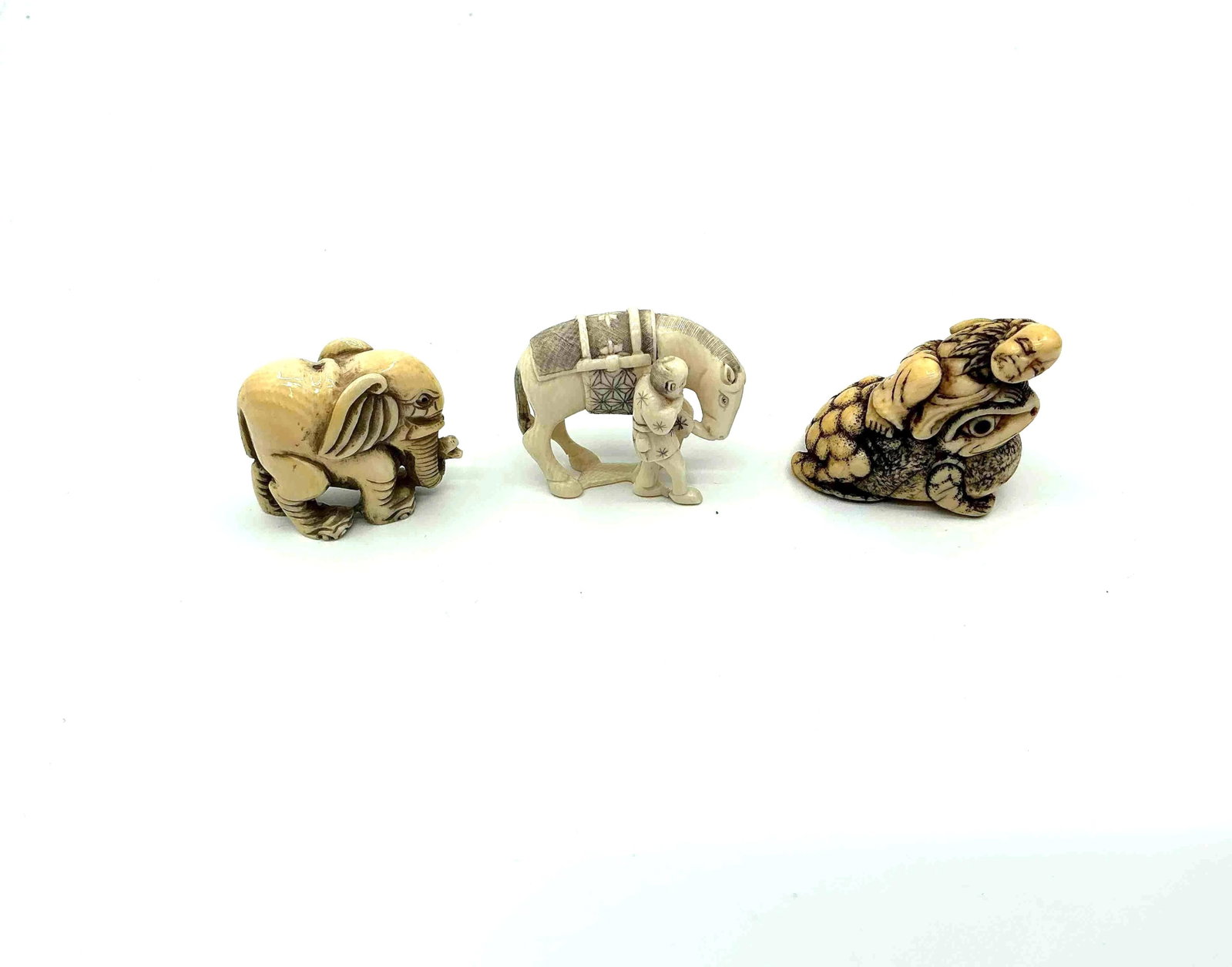 Three Japanese Style Netsuke Animal Figurines: Carved animal figures including two turtles with detailed shells and a small elephant likely crafted from resin or bone imitation material Medium Carved resin or composite material Dimensions Al