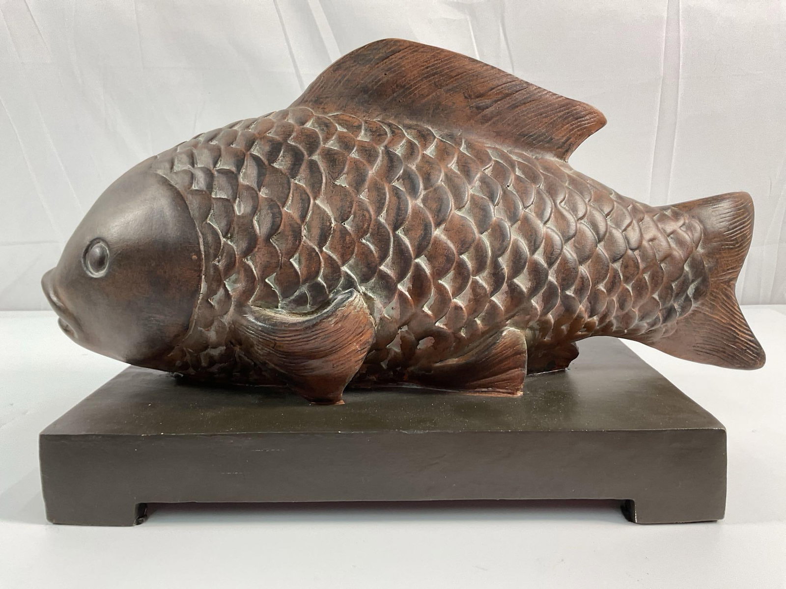 Hand-Carved Wooden Koi Sculpture: This is a hand-carved wooden fish sculpture, likely inspired by Asian cultural symbolism where koi fish or carp represent good fortune, prosperity, and perseverance. The fish is detailed with individu