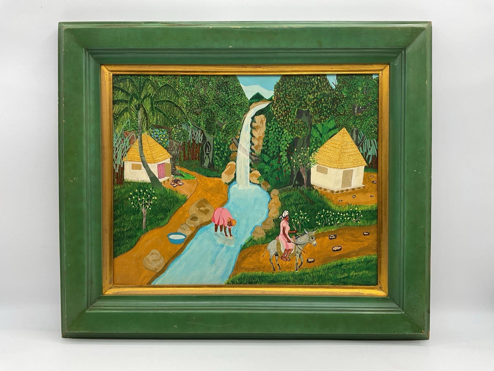 Waterfall Village Scene by Gaston Cyriso, 1993: Artist: Gaston Cyriso Description: Naïve-style Haitian painting depicting a peaceful countryside with two thatched huts, a cascading waterfall, and a woman riding a donkey along a winding path. Brigh