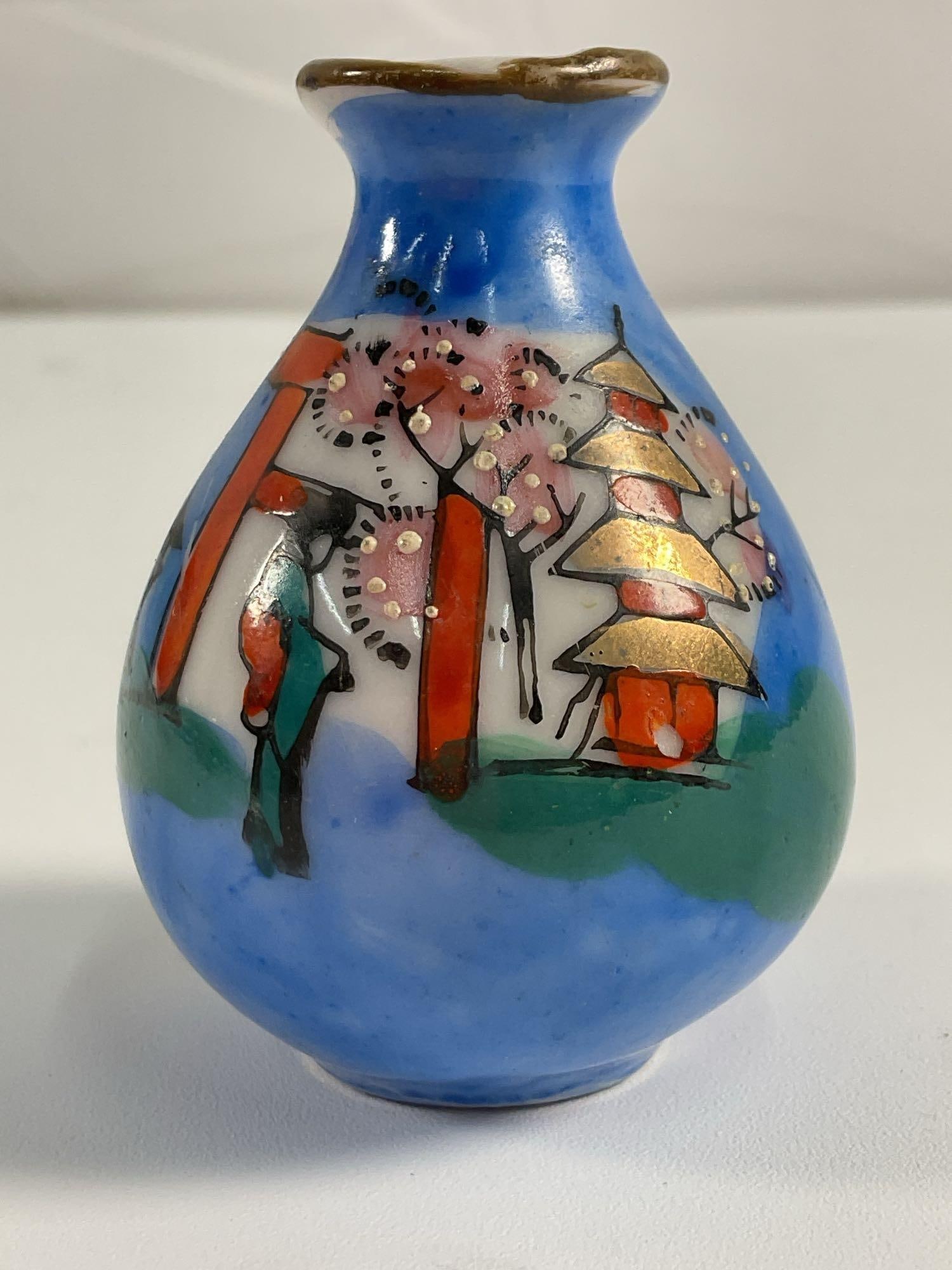 Miniature Japanese Cloisonné Vase: A delicate miniature Japanese cloisonné vase featuring a vibrant hand-painted landscape. The design includes a pagoda surrounded by cherry blossoms, set against a rich blue background that evokes ser