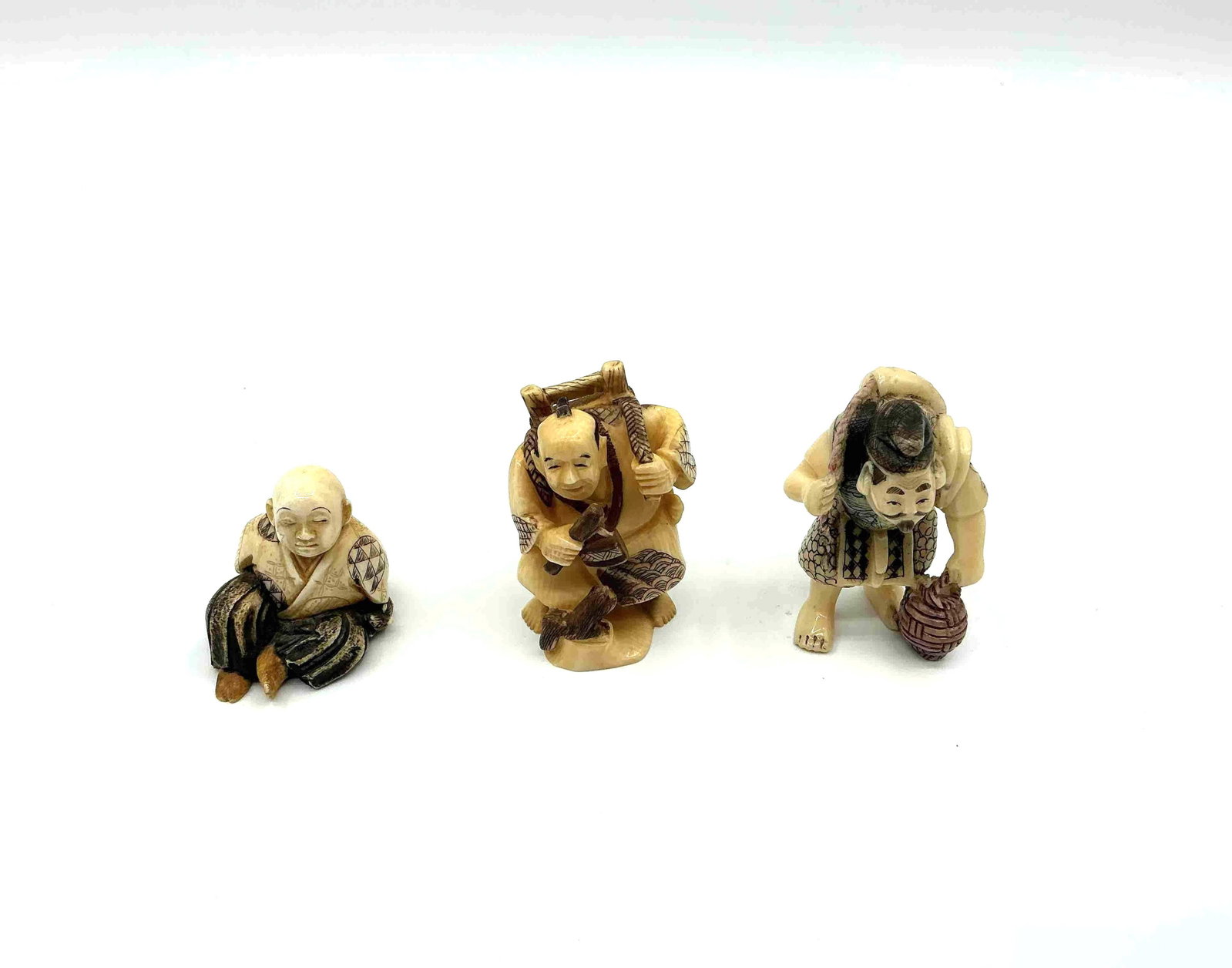 Three Japanese Style Netsuke Figurines: Trio of small carved figures depicting traditional Japanese characters in various poses likely crafted from resin or bone imitation material Medium Carved resin or composite material DIMENSIONS H1in-2