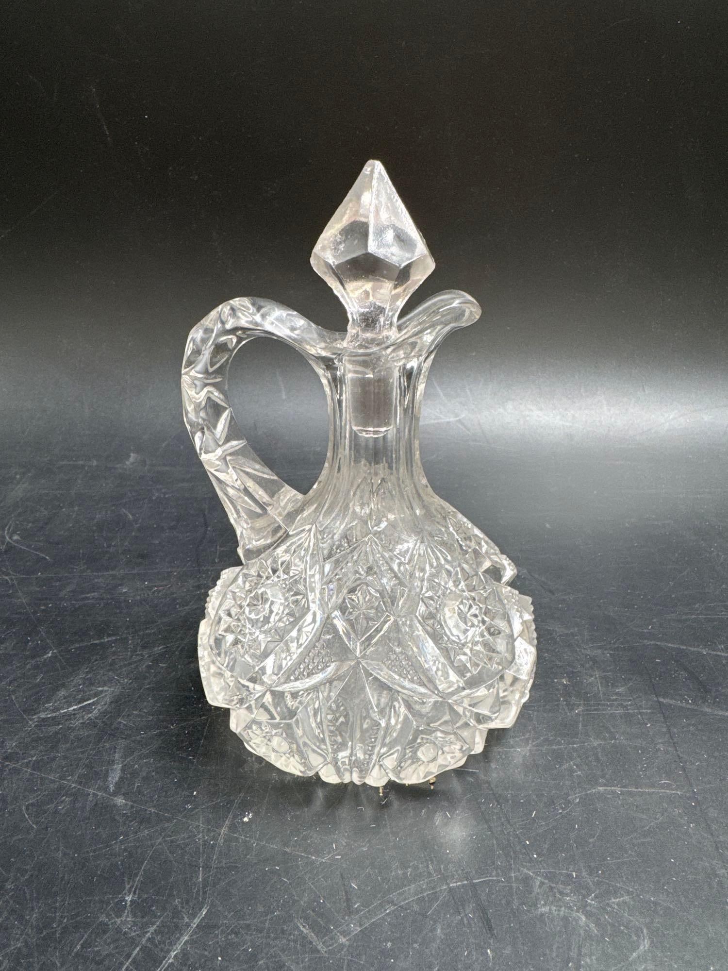 Vintage Cut Glass Cruet with Stopper: Ornate clear cut glass cruet featuring a faceted pointed stopper, scrolled handle, and intricate geometric and floral cut patterns throughout the body. Likely early to mid-20th century, suitable for d