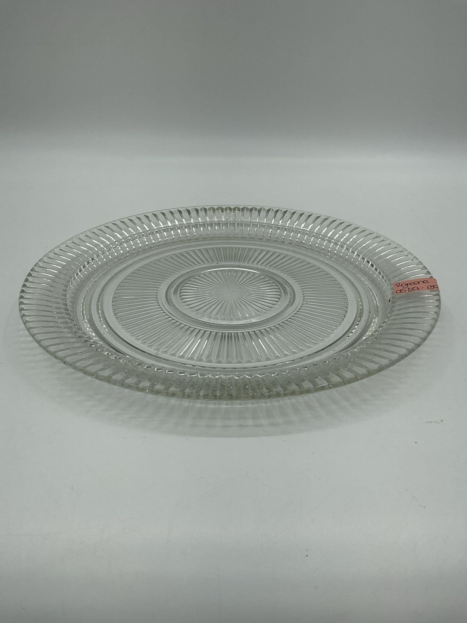 Pressed Glass Dinner Plate with Ribbed Design: Description: Clear glass plate featuring a radial ribbed pattern and a fluted edge. No visible maker’s mark. Dimensions: H:1in Dia:12in