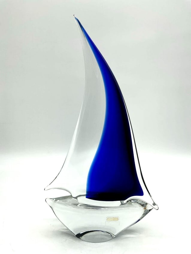 Murano Blue and Clear Glass Sailboat Sculpture: Murano sailboat Elegant Murano sailboat sculpture featuring a gracefully curved cobalt blue sail atop a clear glass hull. Retains original Murano label. A refined decorative piece showcasing Italian c