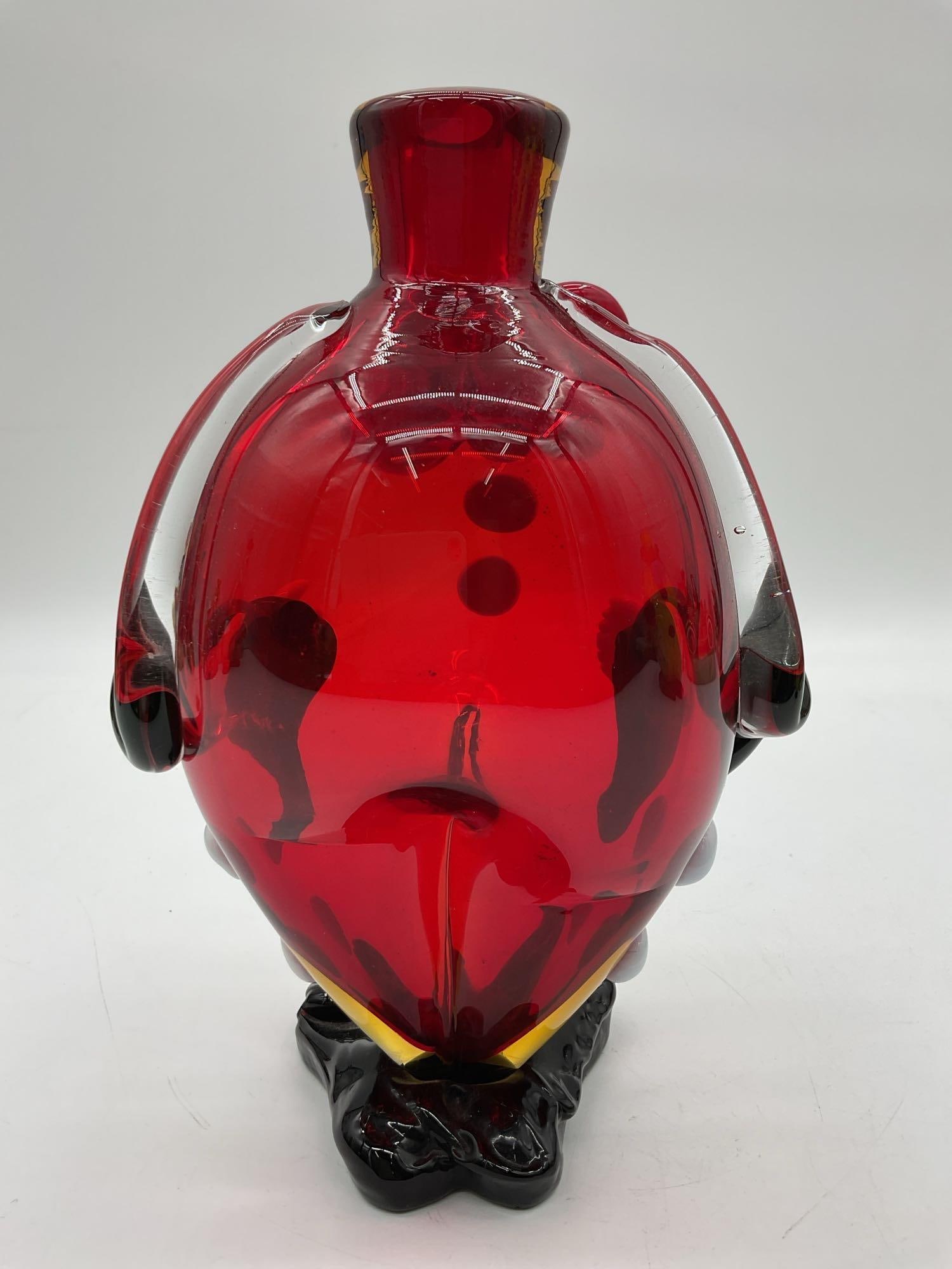 Clown Torso Art Glass Sculpture with Red Bowtie: Whimsical blown glass figure in the shape of a clown's torso, featuring a vivid red body, oversized bowtie, white buttons, and black shoes with expressive hands on hips. Dimensions: H10in L7in W4i
