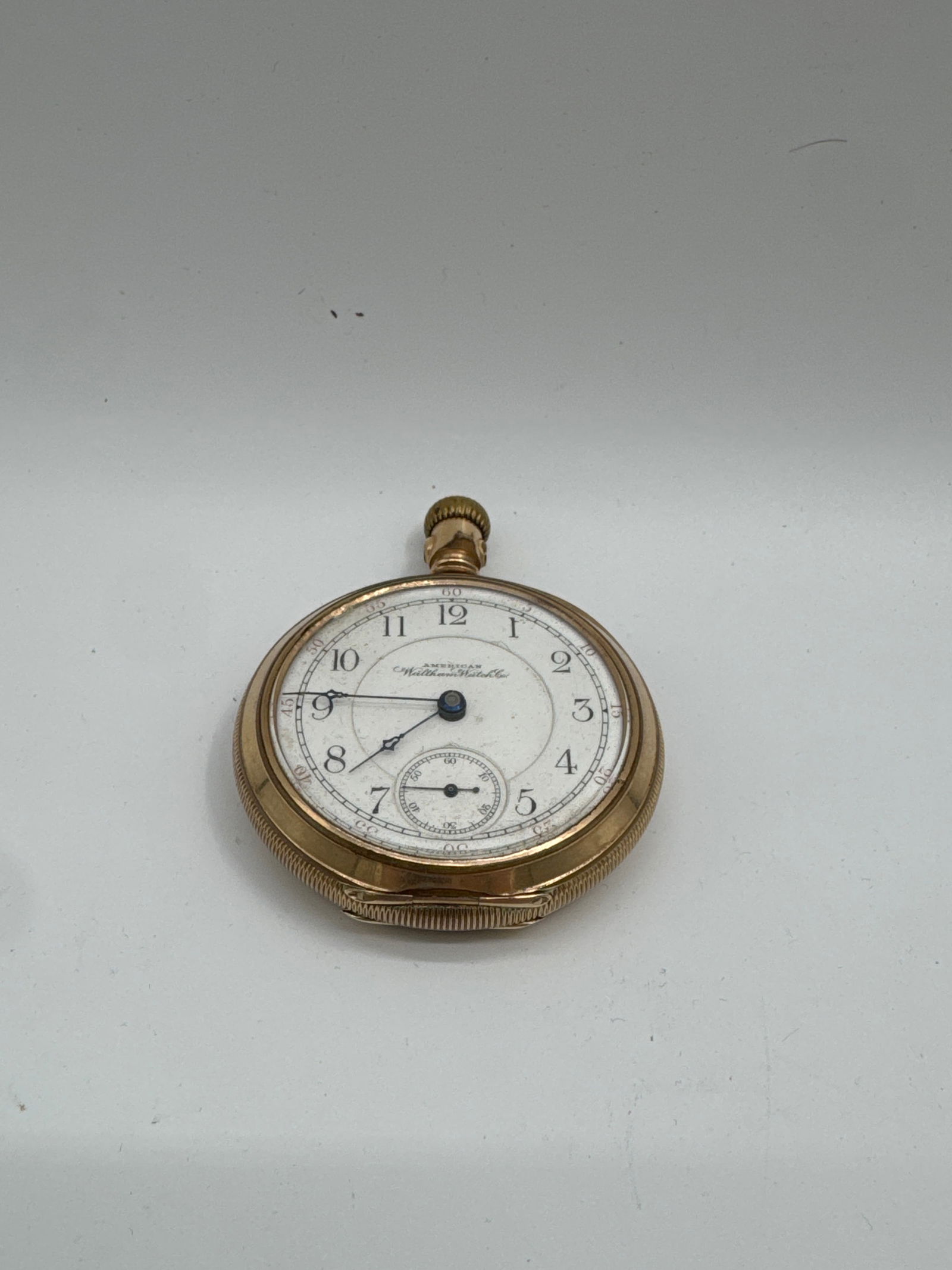 American Waltham Gold-Filled Pocket Watch: American Waltham Watch Co. gold-filled pocket watch. The watch features a white dial with black Arabic numerals and a subsidiary seconds dial. The case is decorated with an engraved floral pattern on