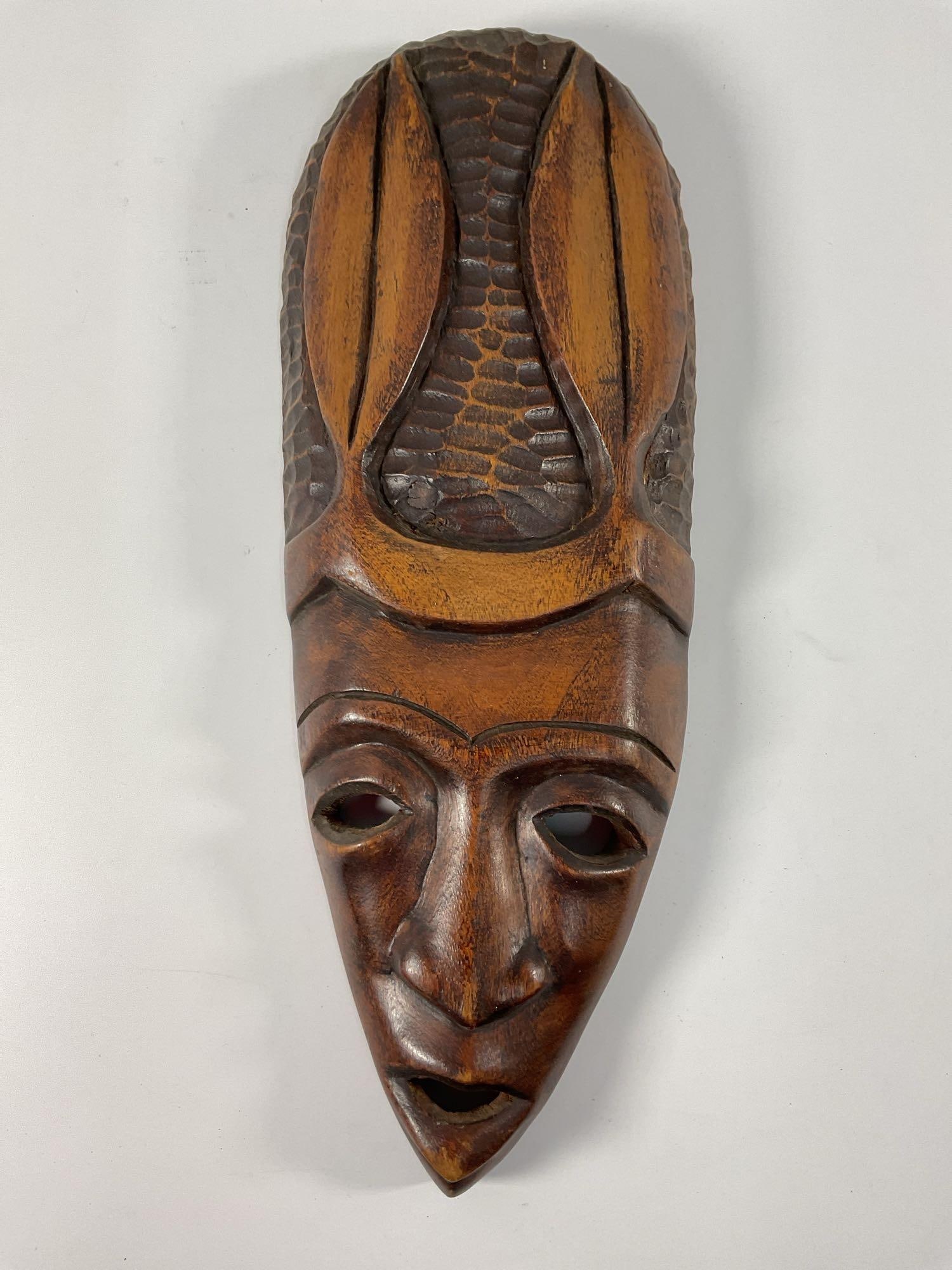 Hand-Carved African Tribal Mask with Animal Motif: A large, hand-carved African tribal mask featuring elongated facial features, bold geometric designs, and an animal motif on the headdress. The intricate carvings and polished wood surface suggest it 