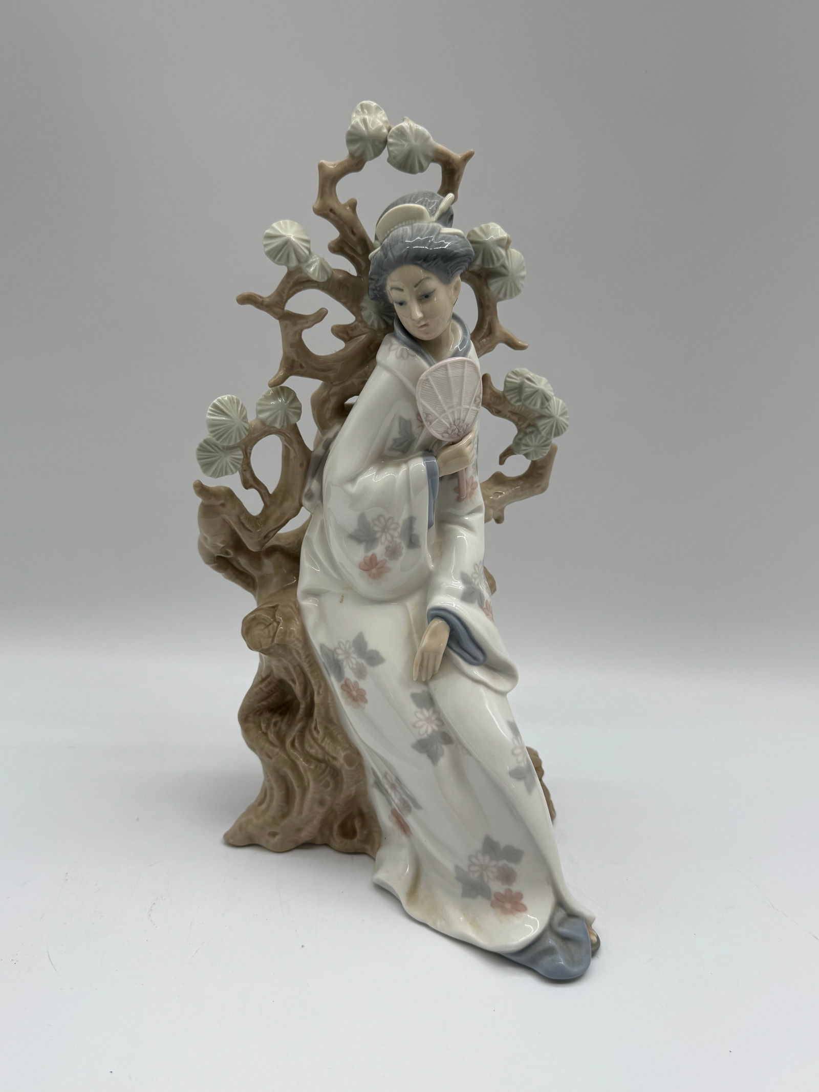 Lladro Porcelain Figurine - Reclining Geisha: Lladro porcelain figurine depicting a reclining geisha resting on a flowering tree branch. Marked on the base 'Lladro Hand Made in Spain' and signed. Dated 11-16-80. Measures approximately 6 i