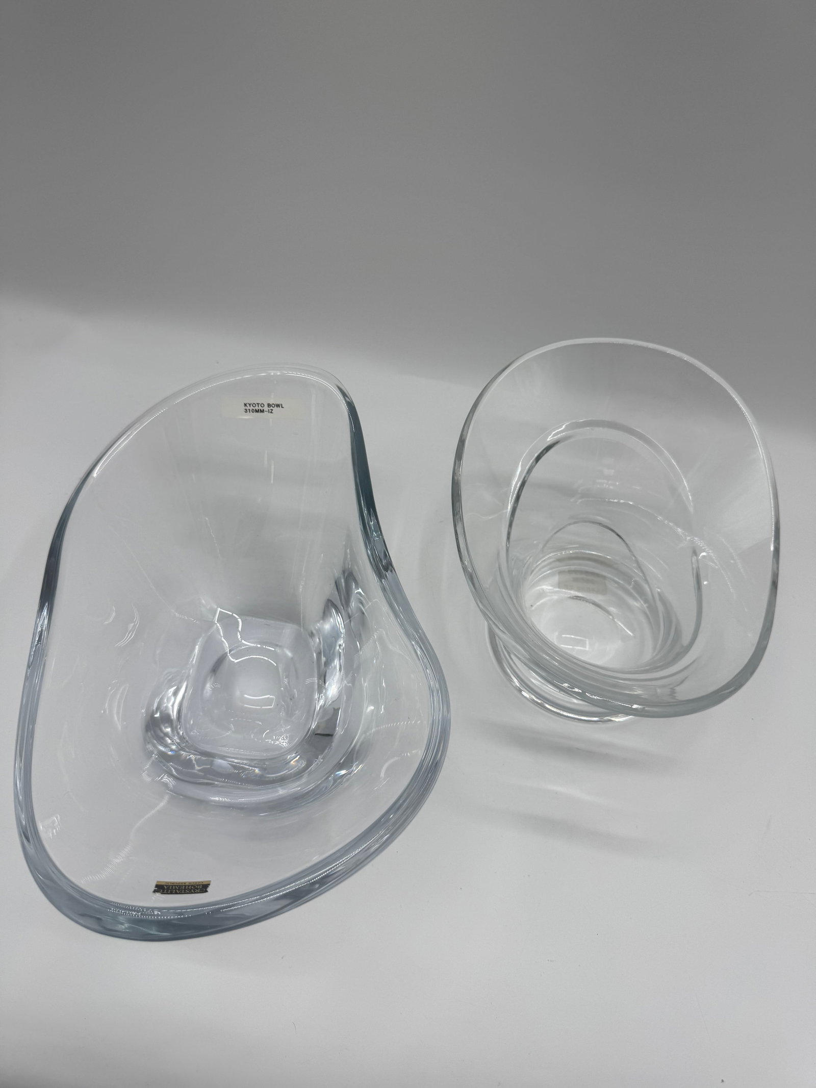 Two Art Glass Bowls: Two clear art glass bowls. One bowl is round with a spiral design. The other bowl is an irregular shape with a square base. Both are unmarked.
