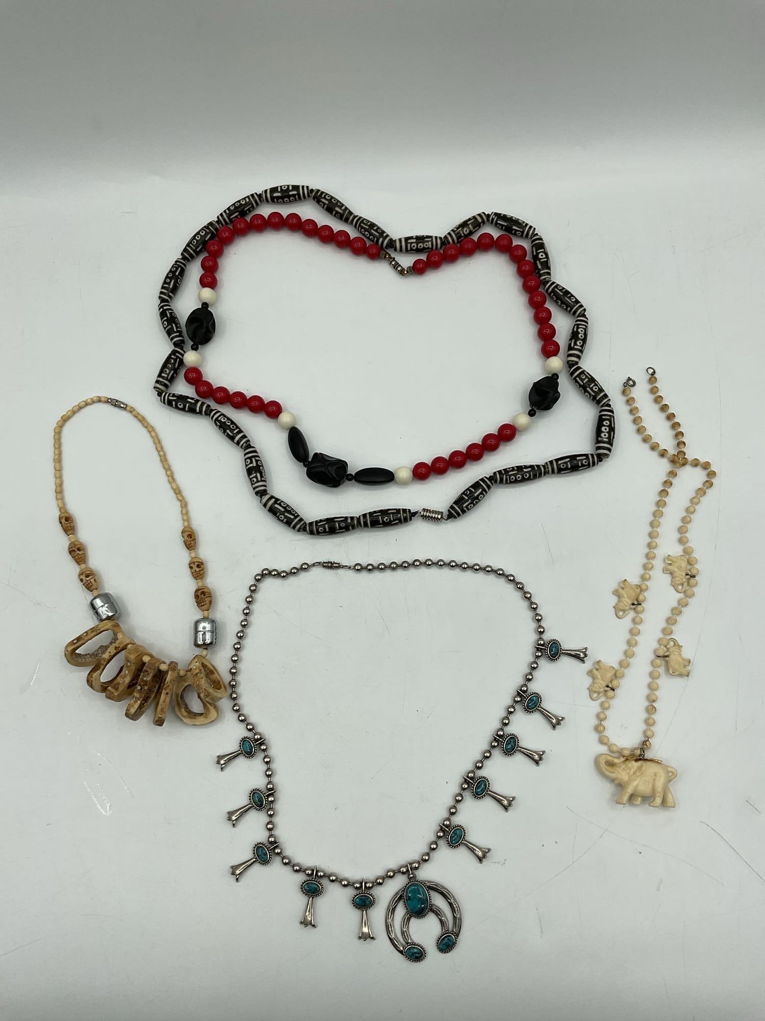 Assorted Vintage Tribal and Costume Jewelry Lot: A vibrant and eclectic collection of tribal and costume jewelry including a red, black, and white beaded necklace with carved animal figures, black and white tribal-patterned stretch bracelets, carved