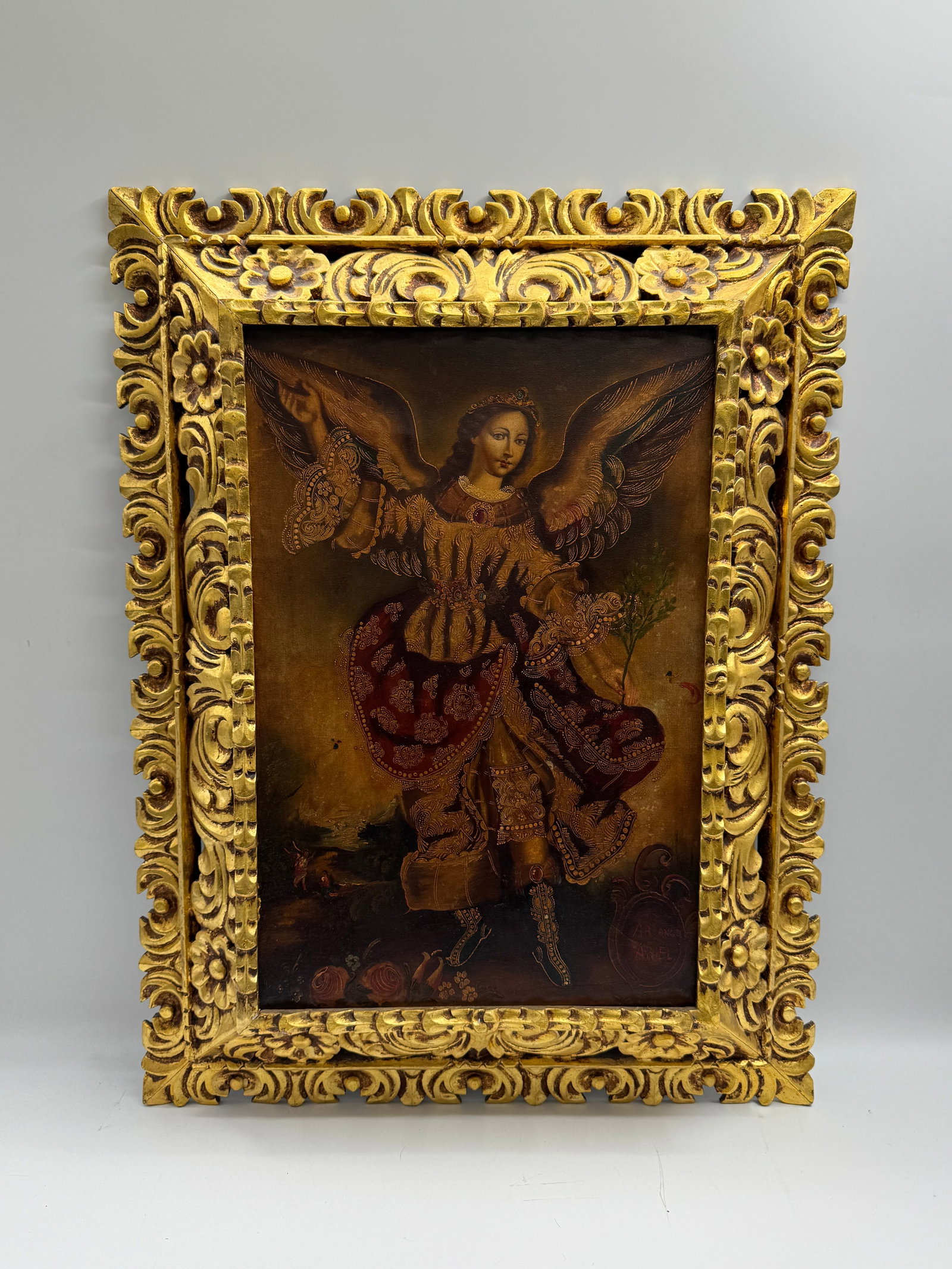 Framed Oil Painting of Archangel: Oil on canvas painting depicting an archangel, possibly Gabriel, in ornate gold frame. Signed in red paint. Dimensions: 33 x 25 inches.