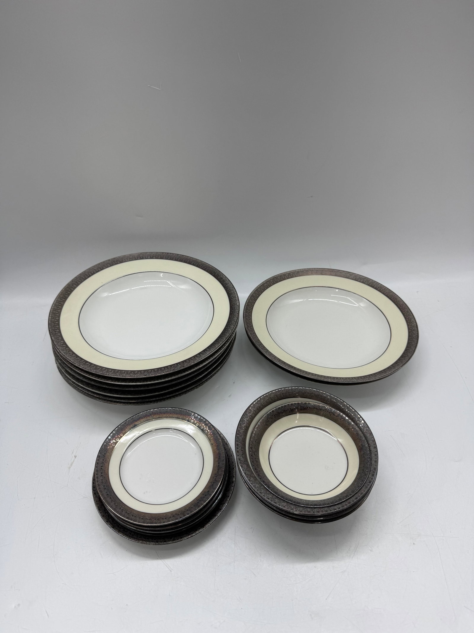 Theodore Haviland Limoges Dinnerware Set: A Theodore Haviland Limoges dinnerware set. The set includes dinner plates, salad plates, and bowls, each with a white center and a brown and cream border. Marked on the bottom.