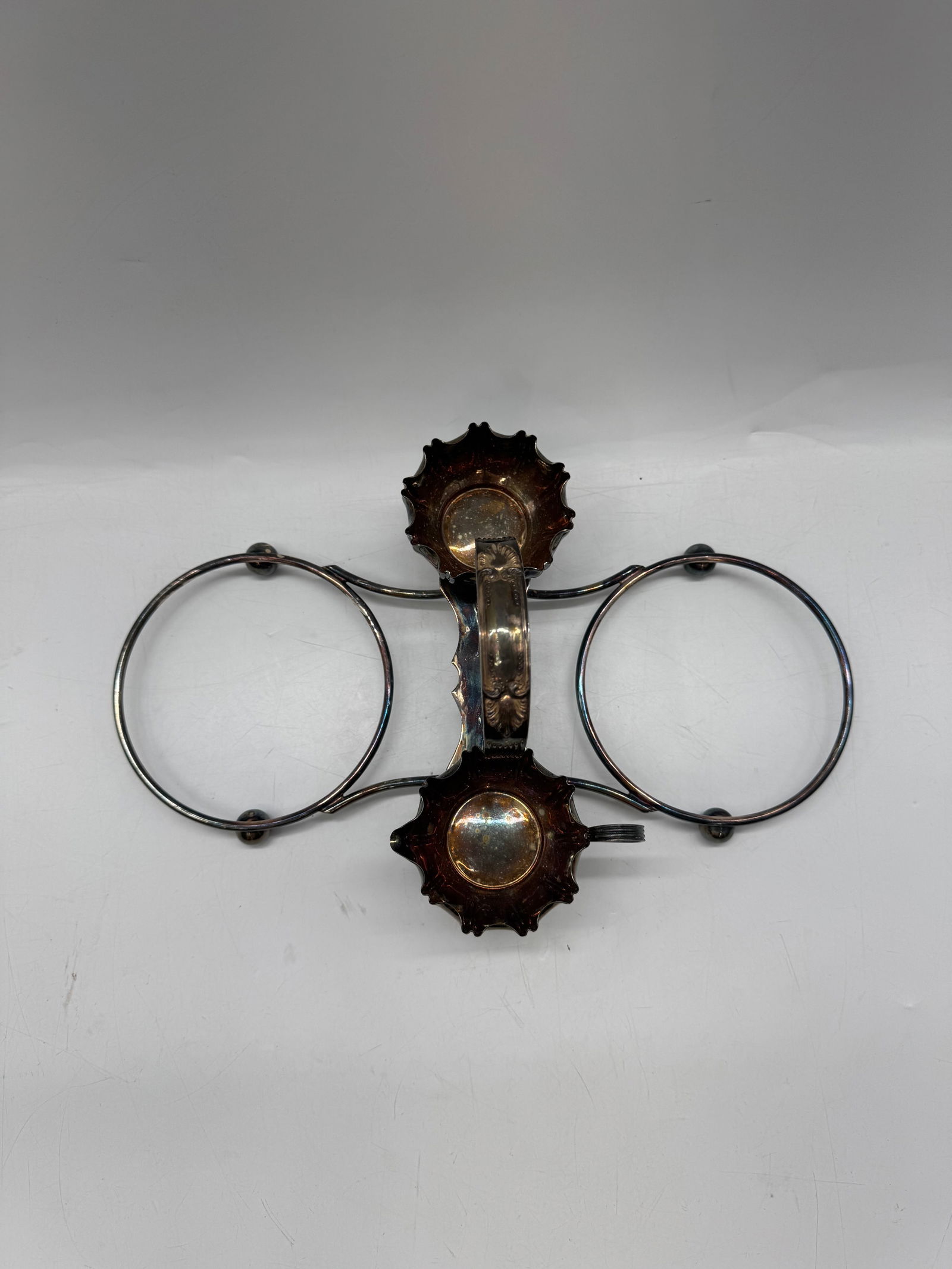 Vintage Silver Plated Wine Bottle Holder: Vintage silver plated wine bottle holder featuring ornate detailing and a circular frame design. Holds two bottles. Dimensions approximately 16x10 inches.