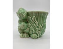 Green Ceramic Bunny Planter or Toothpick Holder: A small vintage figural planter or toothpick holder featuring a rabbit leaning against a leafy, textured vessel. Finished in a glossy celadon green glaze, this mid century novelty piece was likely pro