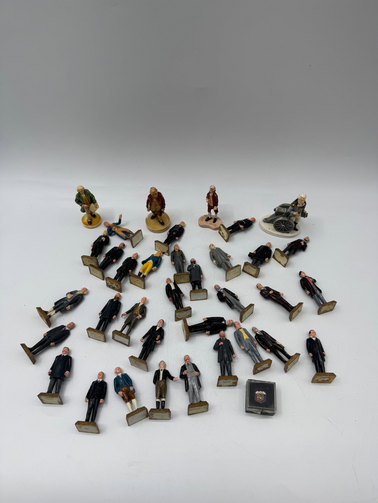 Collection of Vintage Figural Cast Metal Statuettes: Collection of vintage cast metal statuettes, depicting figures in various attire. Heights range from 2.5 to 3.5 inches. Includes a variety of poses and clothing styles. Some figures are on bases.