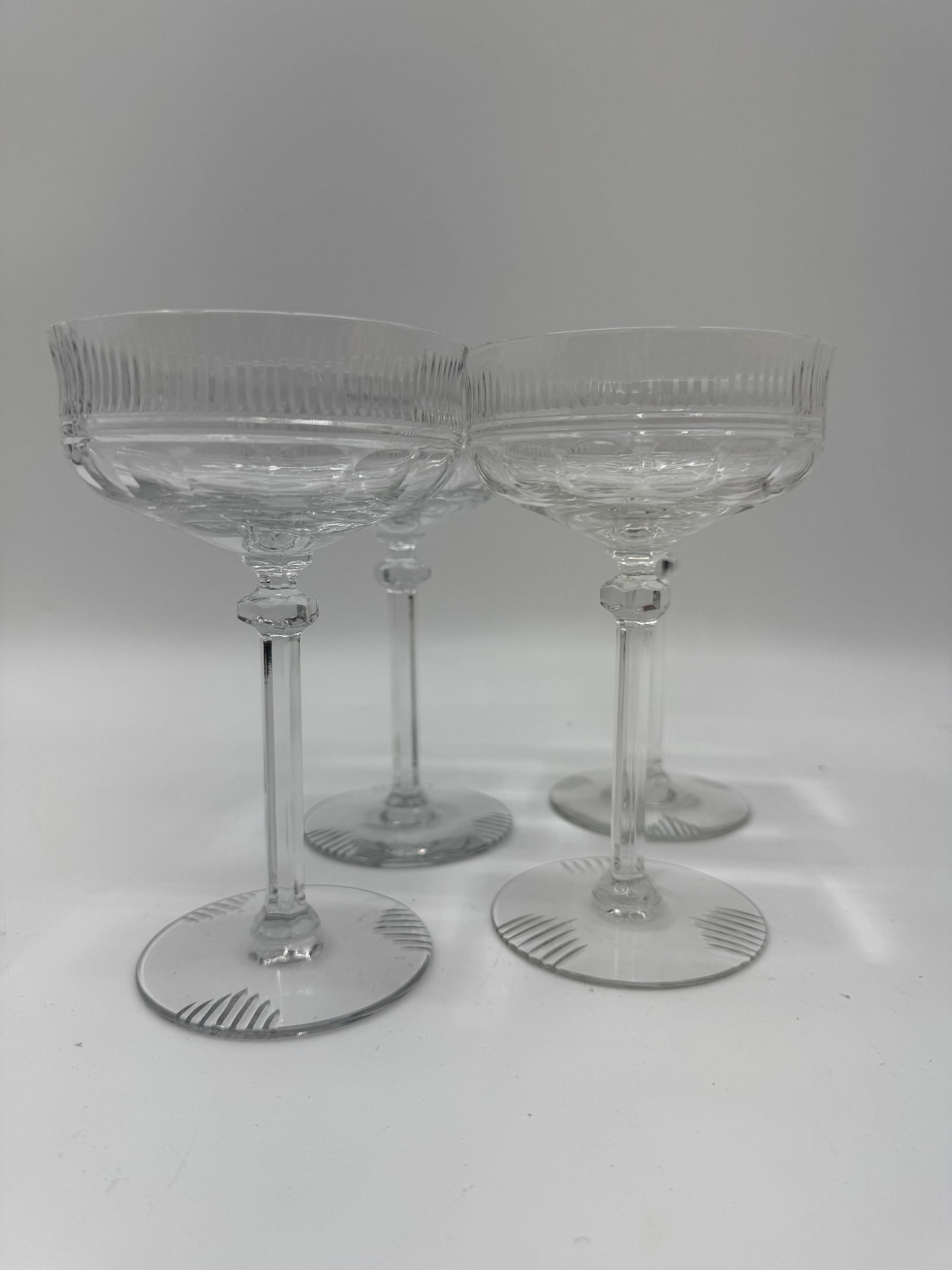 Set of 4 Cut Crystal Champagne Coupes: Elegant set of four cut crystal champagne coupes featuring fluted bowl designs and faceted stems. These refined glasses reflect light beautifully, ideal for formal dining or vintage-style entertaining