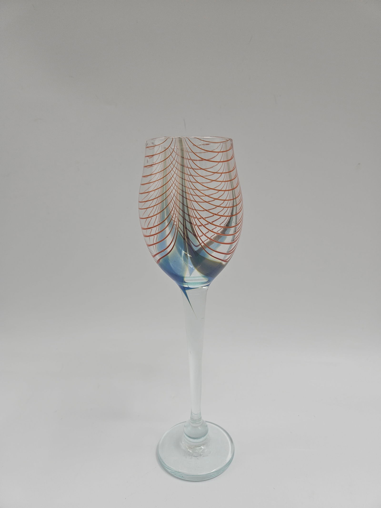 Hand-Blown Art Glass Wine Goblet: Elegant hand-blown art glass goblet featuring a clear stem and bowl with iridescent sheen and delicate red spiral threading design. Exhibits fine craftsmanship and fluid symmetry. Dimensions: H: 10 in