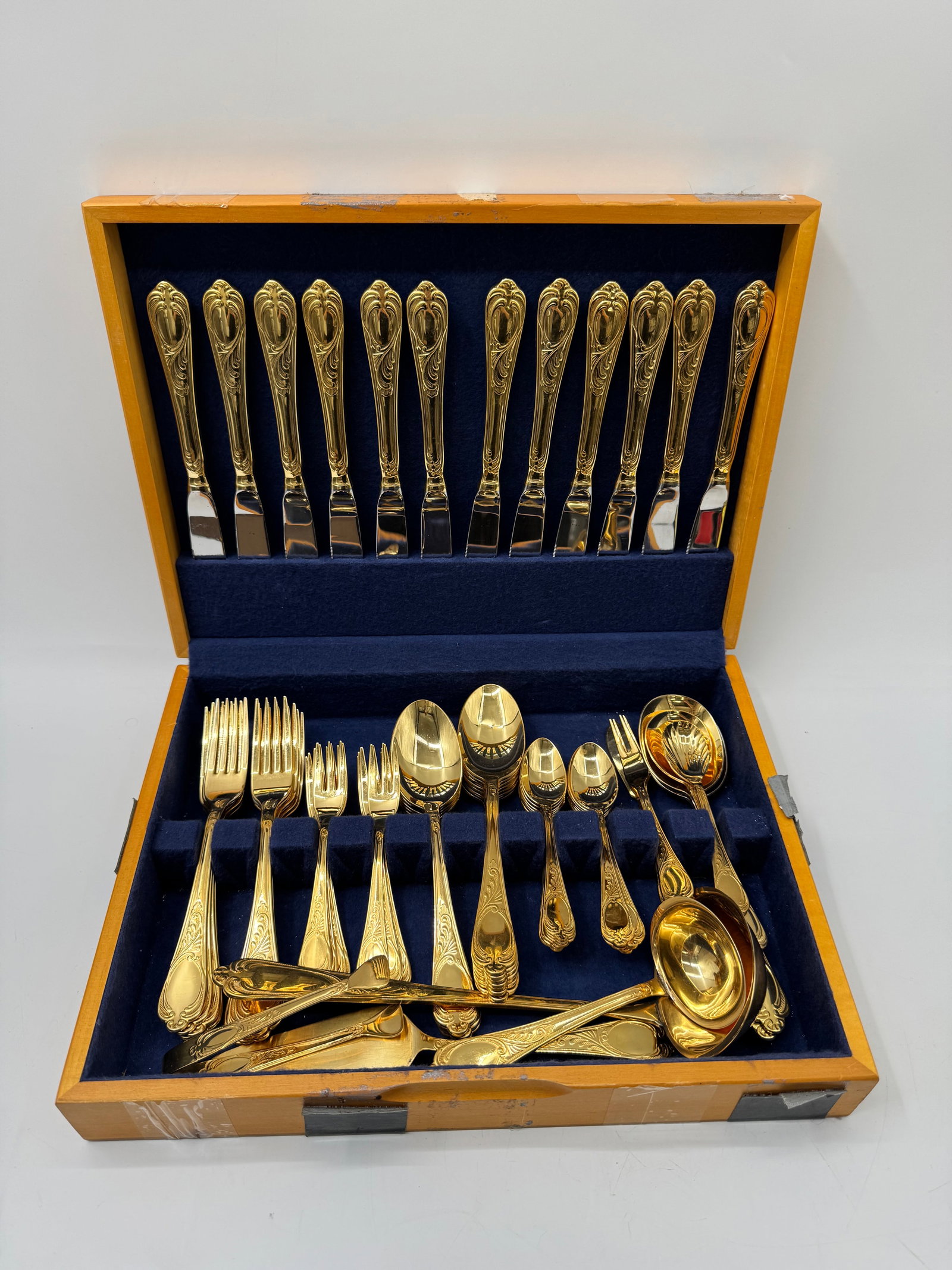 23/24k Gold Plated 72-Piece Cutlery Set, Solingen Germany: A 72-piece cutlery set, 23/24k gold plated, marked 18/10 Solingen Germany. Includes knives, forks, spoons, and serving pieces. Presented in a fitted wooden case with blue velvet lining. Case measures 
