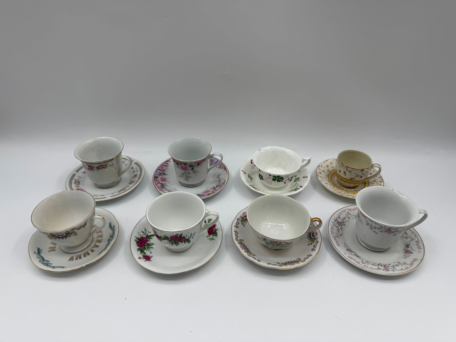 Collection of Eight Decorative Tea Cups and Saucers: Collection of eight decorative tea cups and saucers. Each cup and saucer features a unique floral design. Cups range from 2-3 inches in height and 3-4 inches in width. Saucers are approximately 6 inch