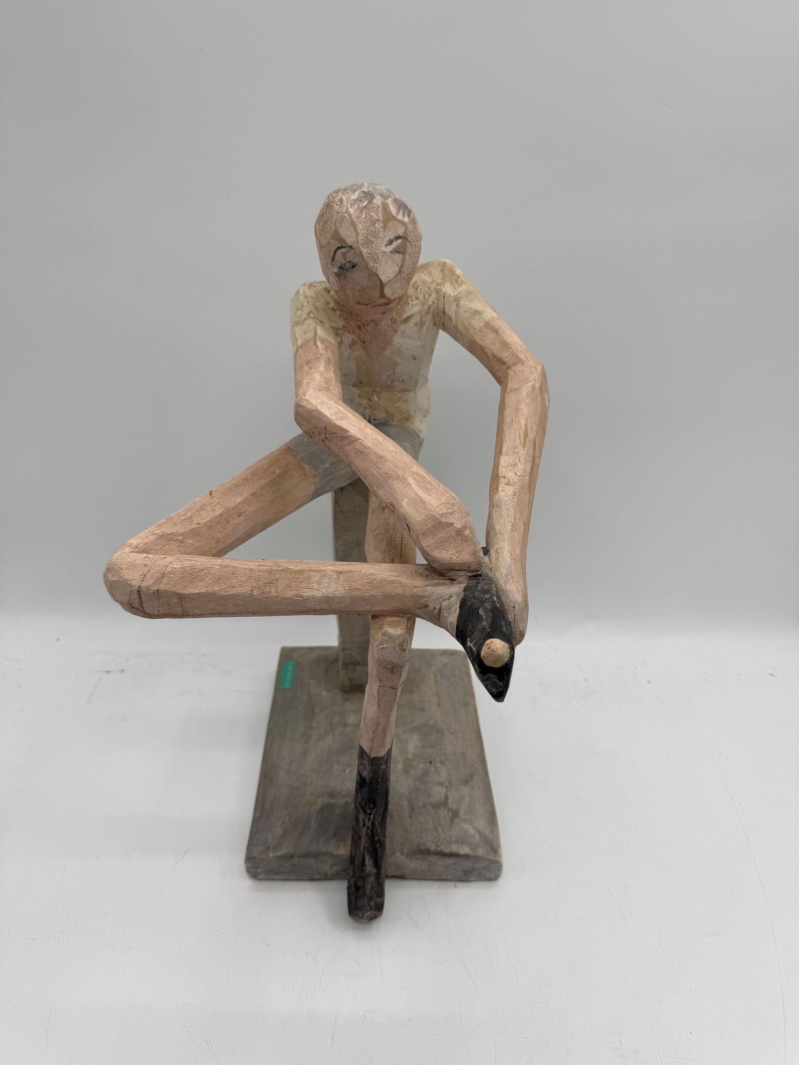 Folk Art Carved Wood Figure: Carved wood figure depicting a reclining figure with legs raised. Mounted on a wood block. Approximate dimensions: 19 x 8 x 10 inches.