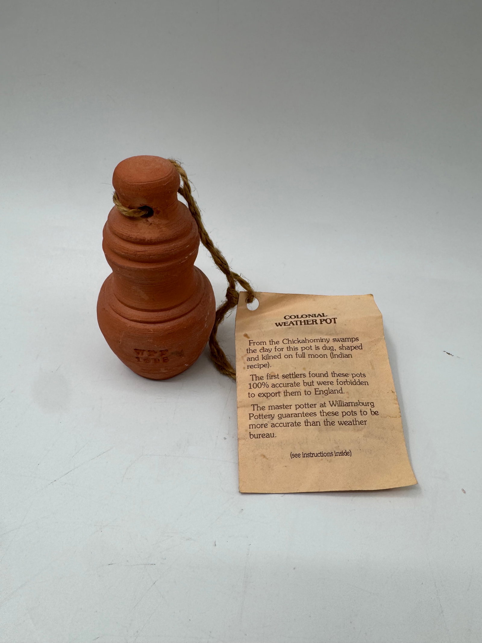 Colonial Weather Pot: Terracotta Colonial Weather Pot with tag. The tag reads: From the Cotswolds, England. The pot changes color to indicate weather conditions.