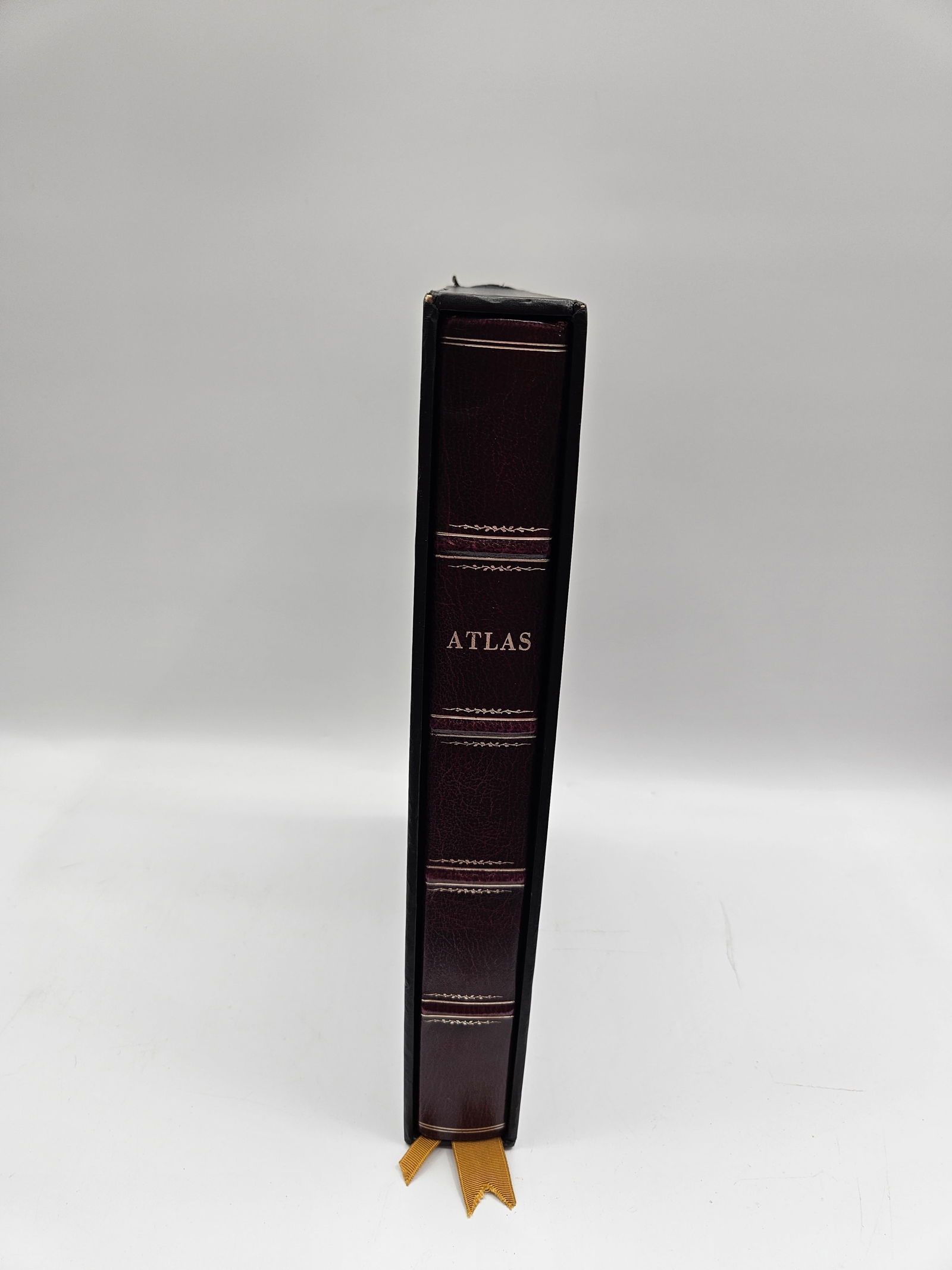 Leather Bound Atlas: Leather bound atlas with gilt compass rose design on the cover. The book has a marbled paper border and a black outer border. Includes a ribbon bookmark.
