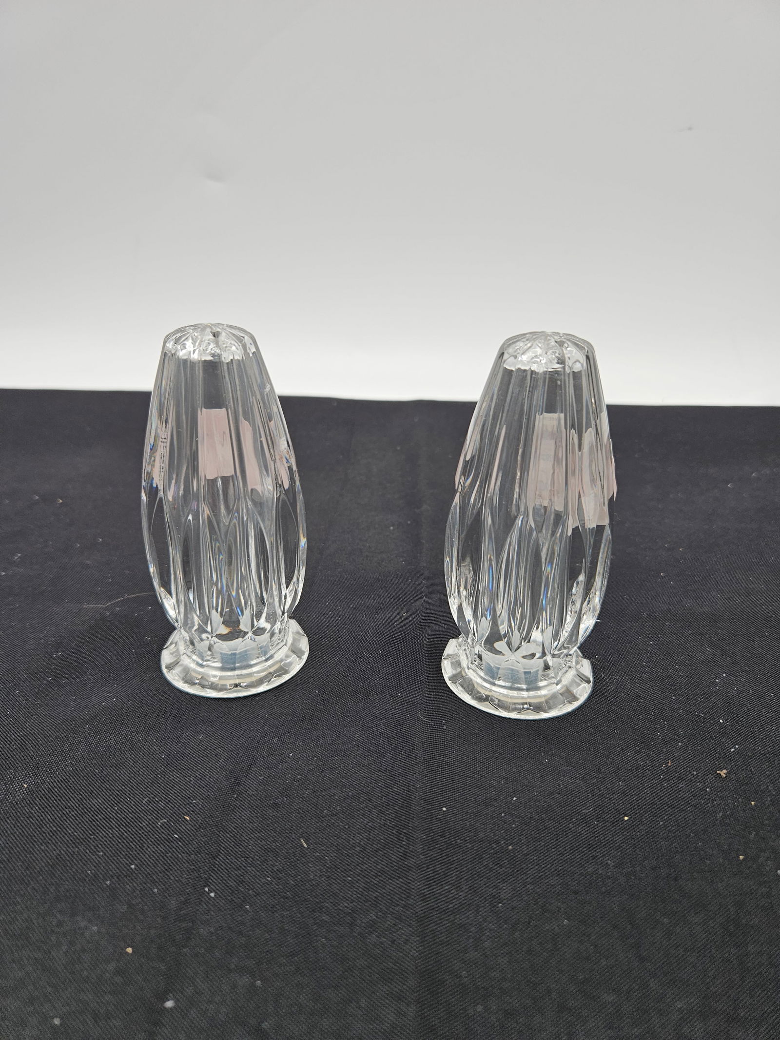 : Pair of Cut Crystal Salt and Pepper Shakers: Classic clear cut crystal salt and pepper shakers featuring vertical faceted design and screw-top lids. Likely mid to late 20th century, elegant and timeless additions to a formal dining table or crys