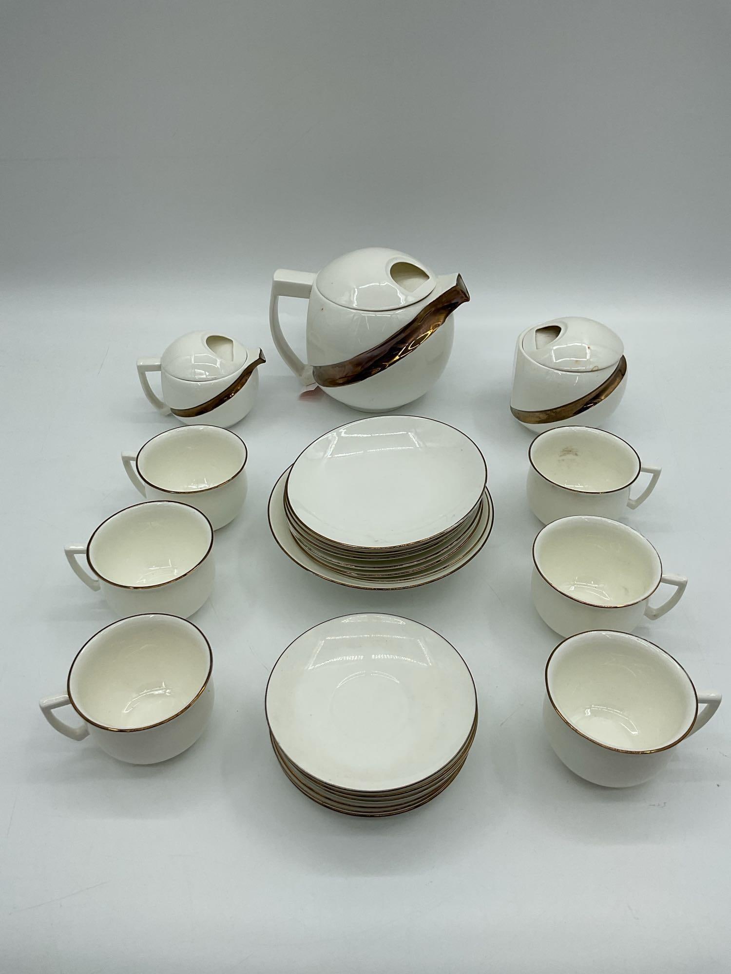 Jiesia Fine Bone China Tea Set, Lithuania:  Elegant white fine bone china tea service set by Jiesia, Lithuania. Includes teapot, sugar bowl, creamer, cups, and saucers, all trimmed with fine gold edging. Known for its minimalist form and