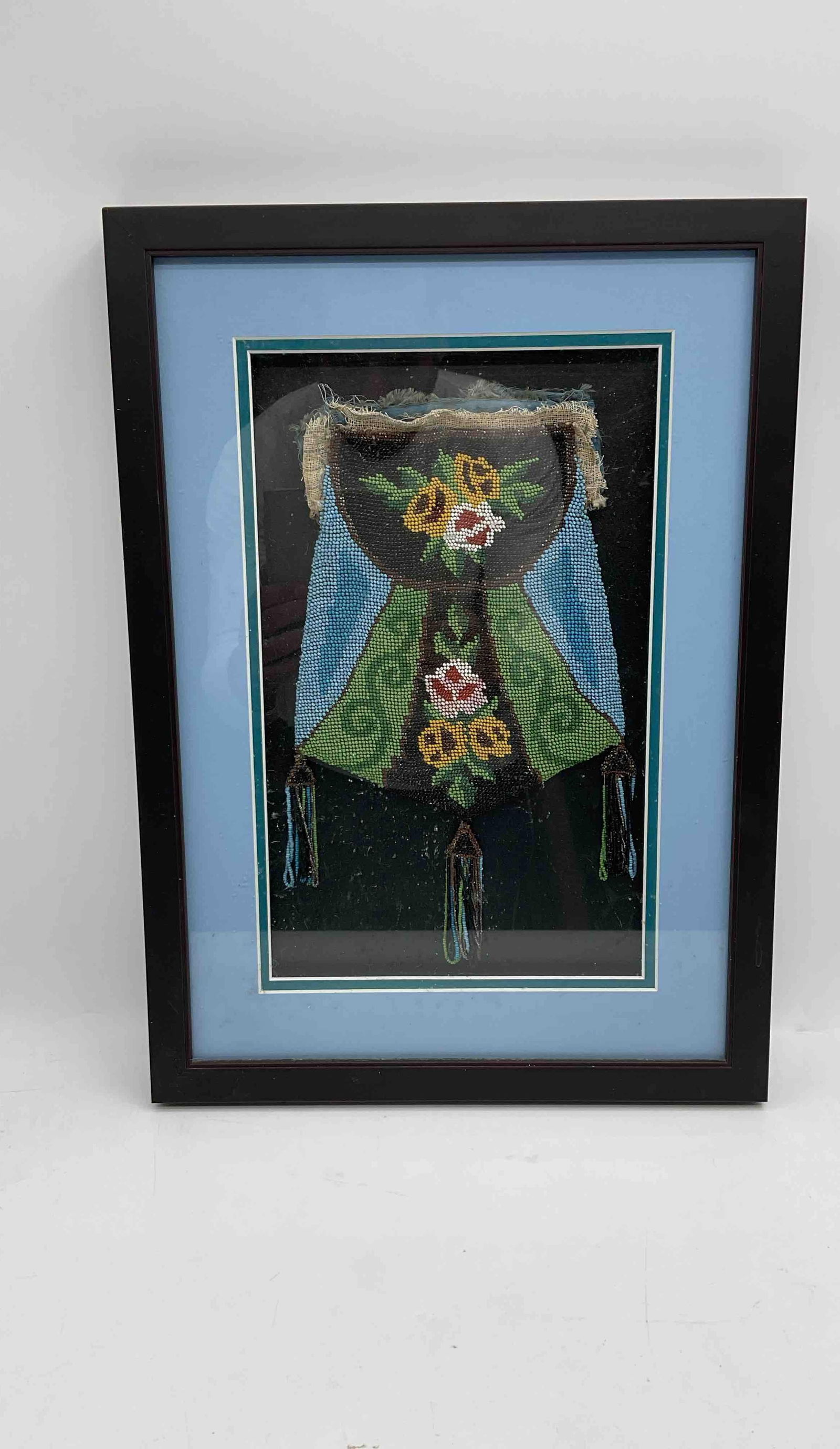 Framed antique beaded purse: Handcrafted needlepoint textile featuring a floral motif in a decorative vase with colorful flowers in green, yellow, and pink tones. Nicely framed under glass with a blue mat, making it suitable for