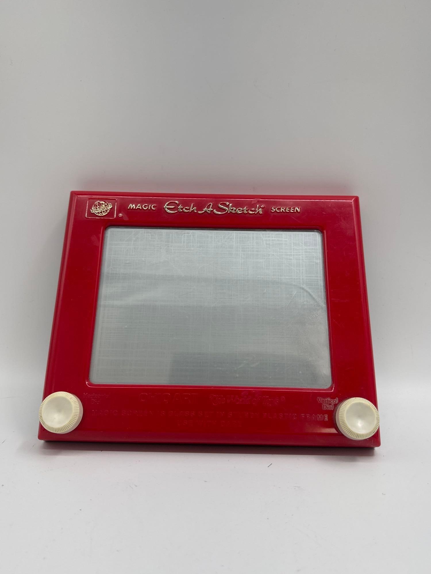 Vintage Etch A Sketch: Classic red-framed Etch A Sketch by Ohio Art, featuring the iconic "Magic Screen" with dual white control knobs for horizontal and vertical drawing. Likely from the late 20th century, this n