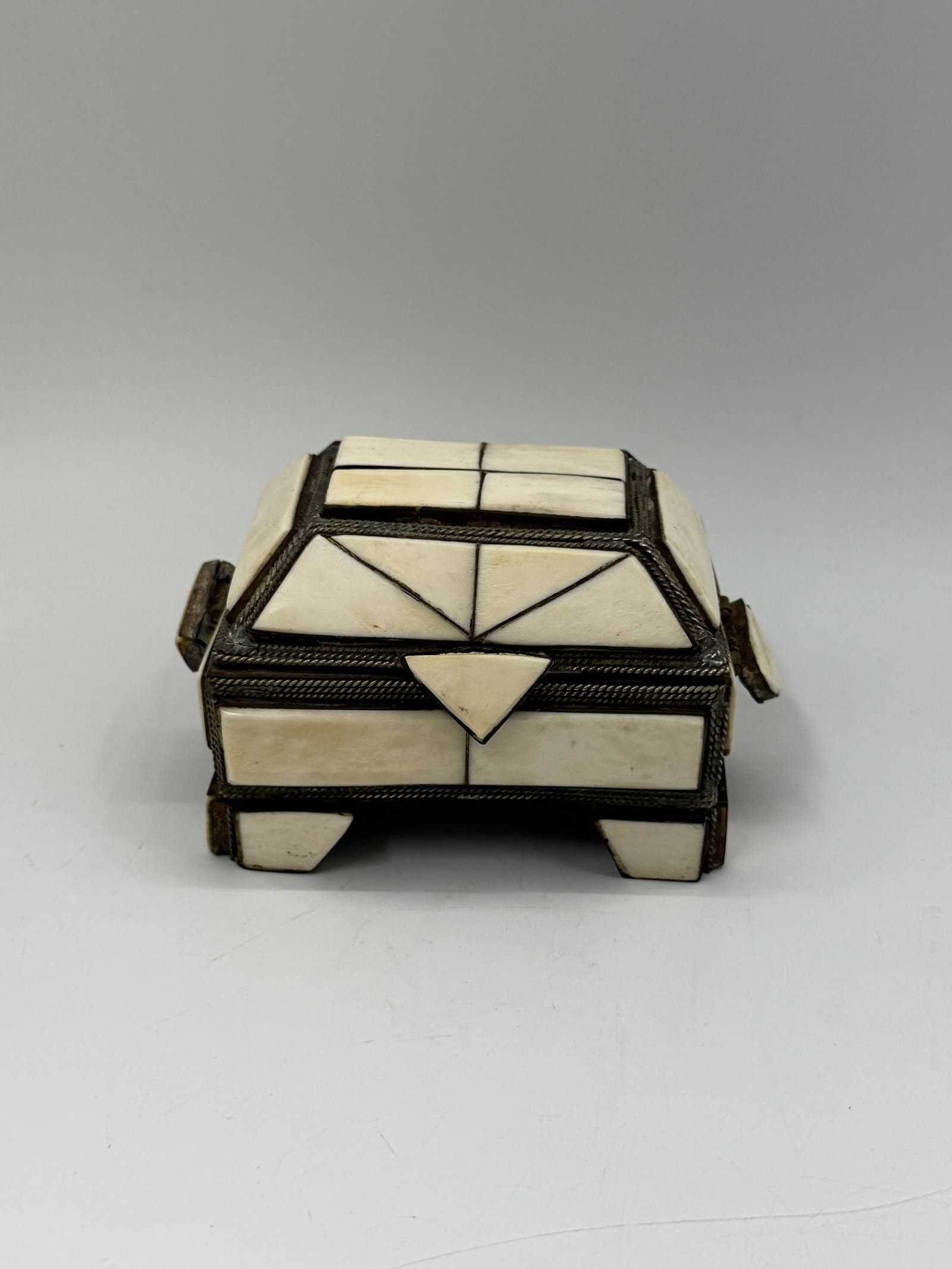 Decorative Bone Inlay Jewelry Box: Square handcrafted jewelry or trinket box featuring geometric bone inlay panels framed in brass or metal. Hinged lid opens to a velvet-lined interior. Elegant and rustic design with artisan detailing.