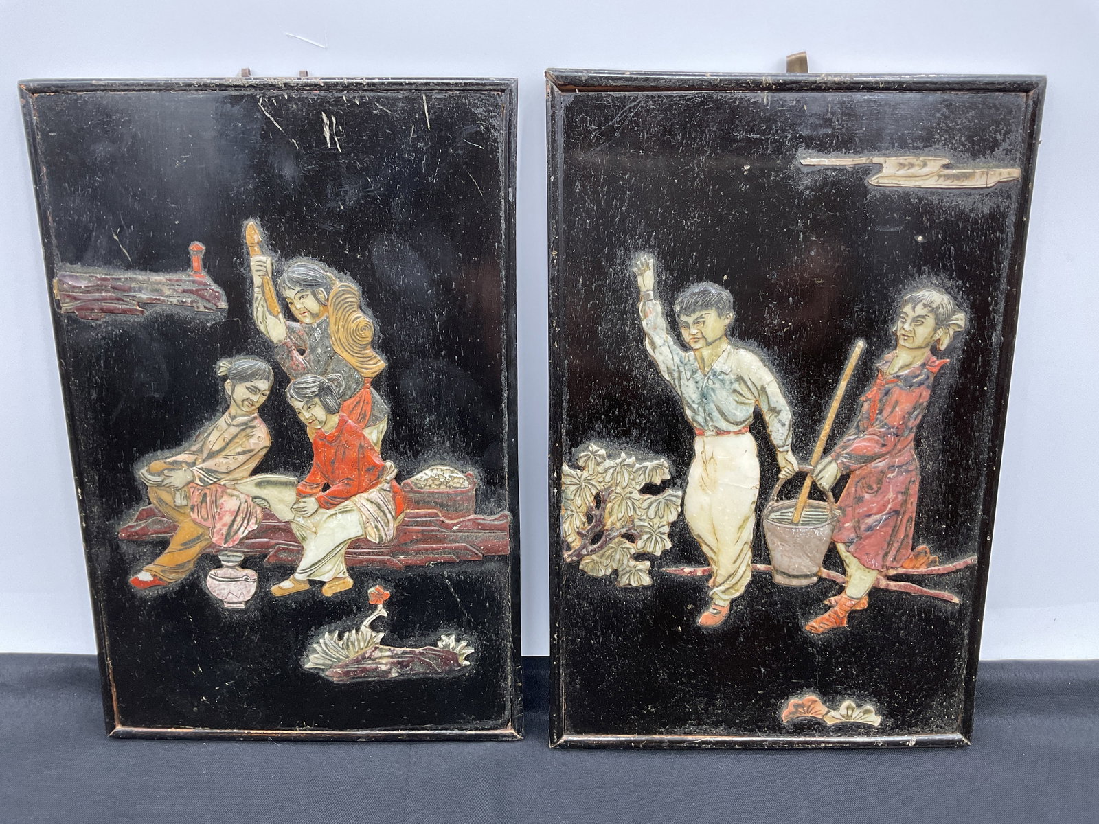 Pair of Chinese Cinnabar & Mother of Pearl Inlay Panels: A pair of framed Chinese panels featuring black cinnabar and mother of pearl inlay depicting figures in a landscape. Each panel measures approximately 12 inches in height and 8 inches in length. Some